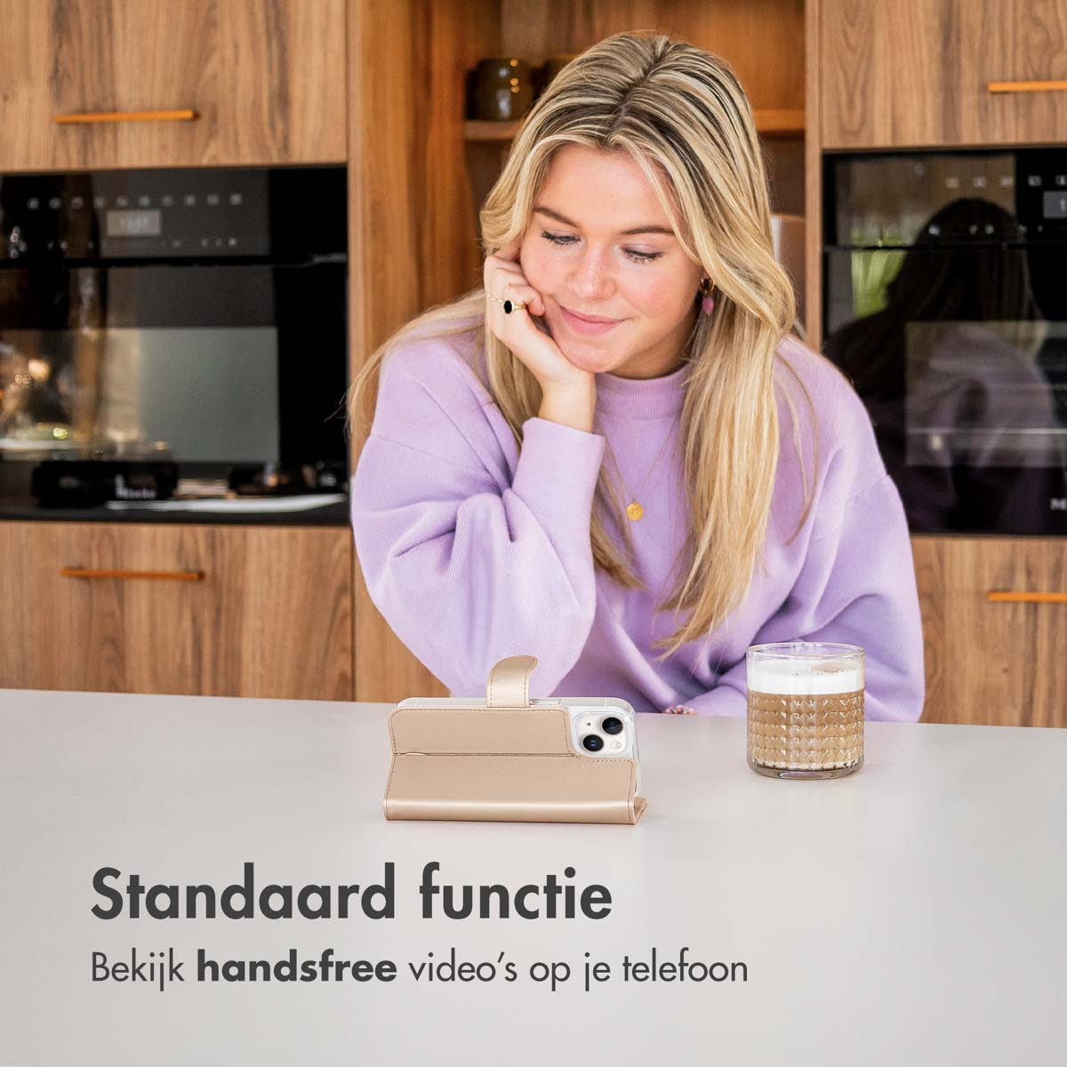 Vrouw in paars trui kijkt naar telefoon in standaard naast koffie.