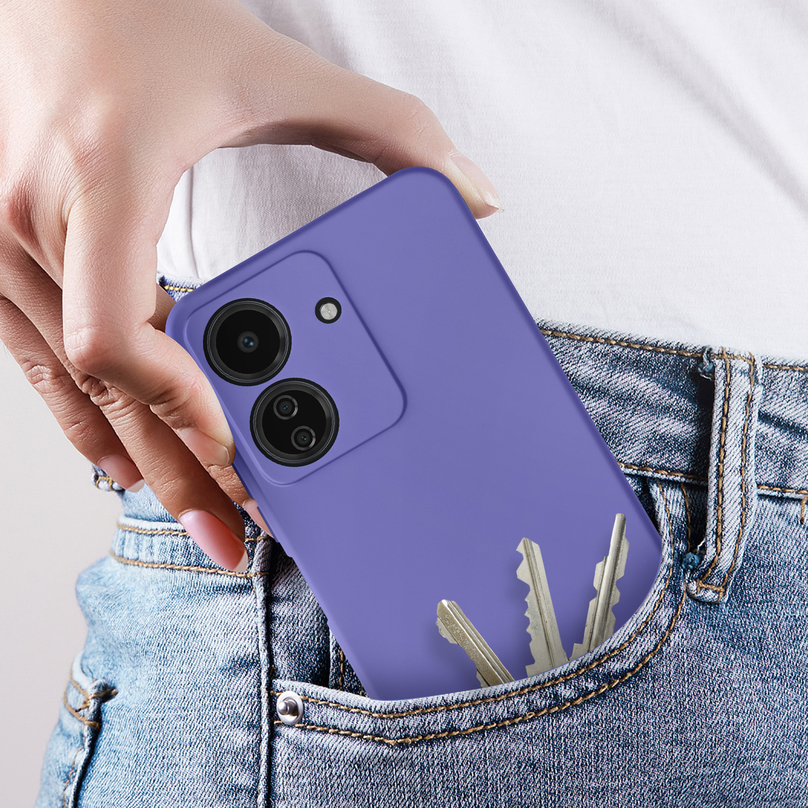 Una mano che tiene un telefono viola in una tasca dei jeans con delle chiavi.