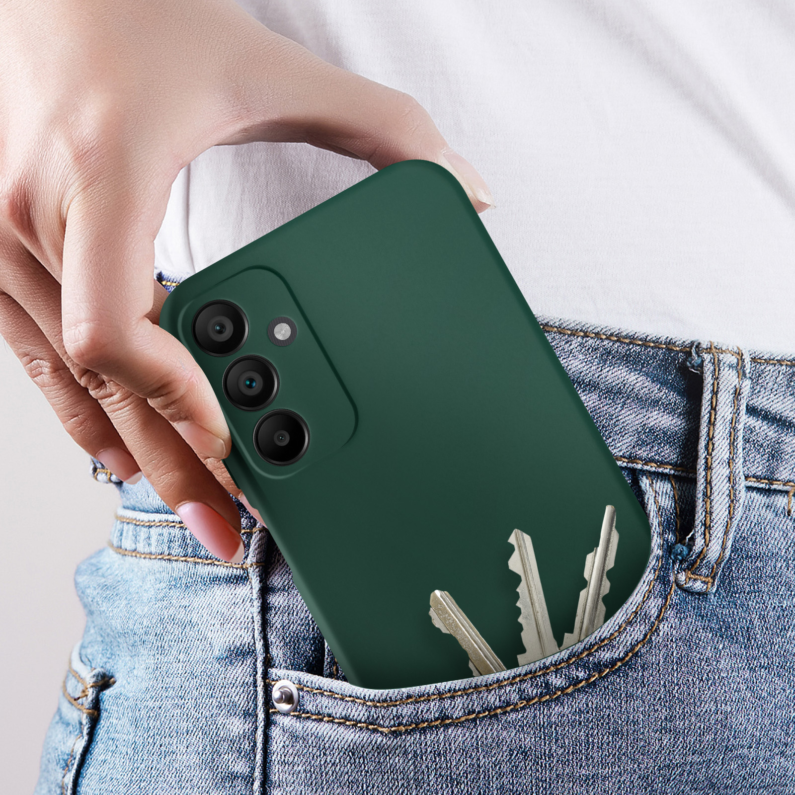 Una mano che tiene uno smartphone verde con chiavi in tasca. Si vedono dei jeans.