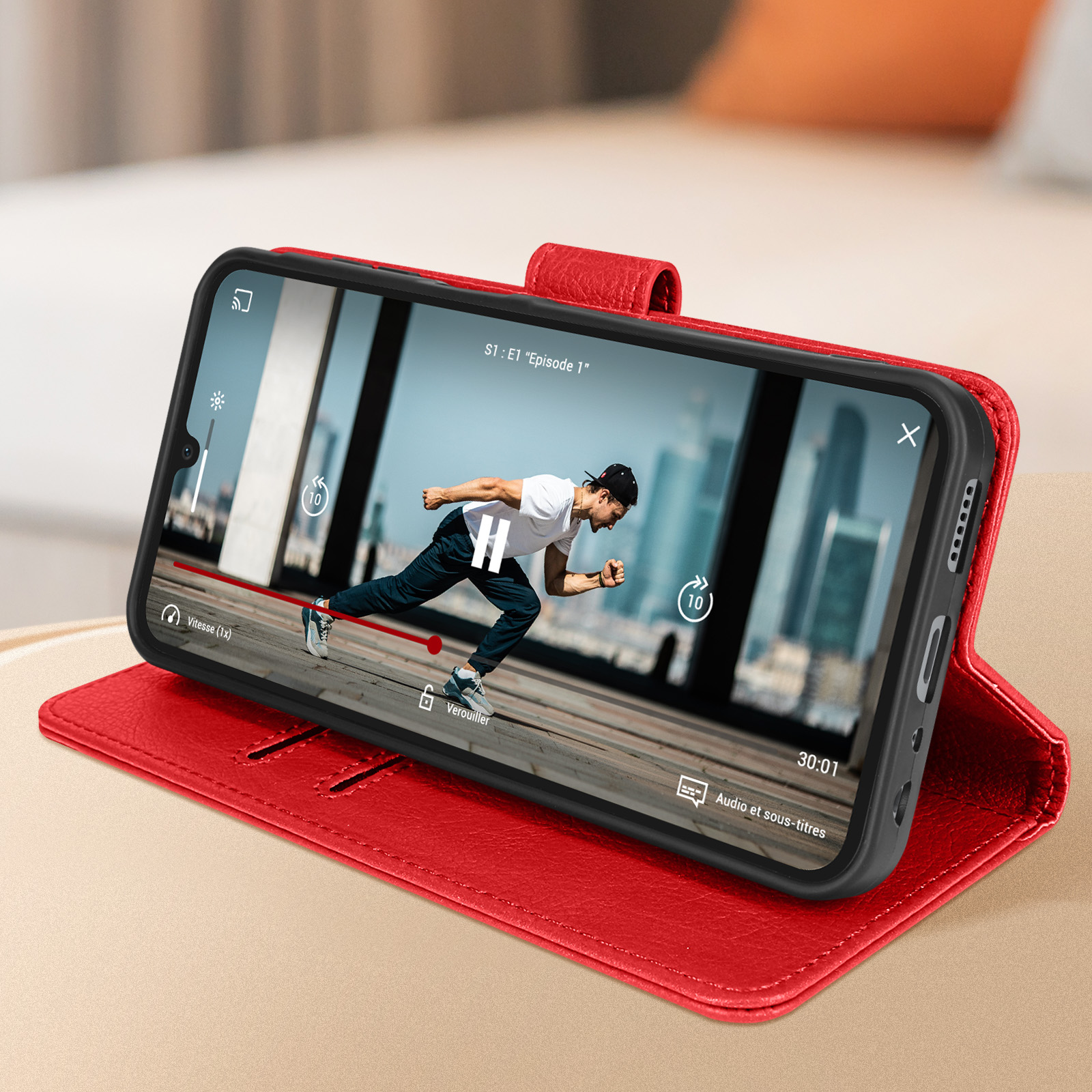 Un telefono in una custodia a portafoglio rossa, che mostra un video in riproduzione sullo schermo. Un uomo corre nel video.