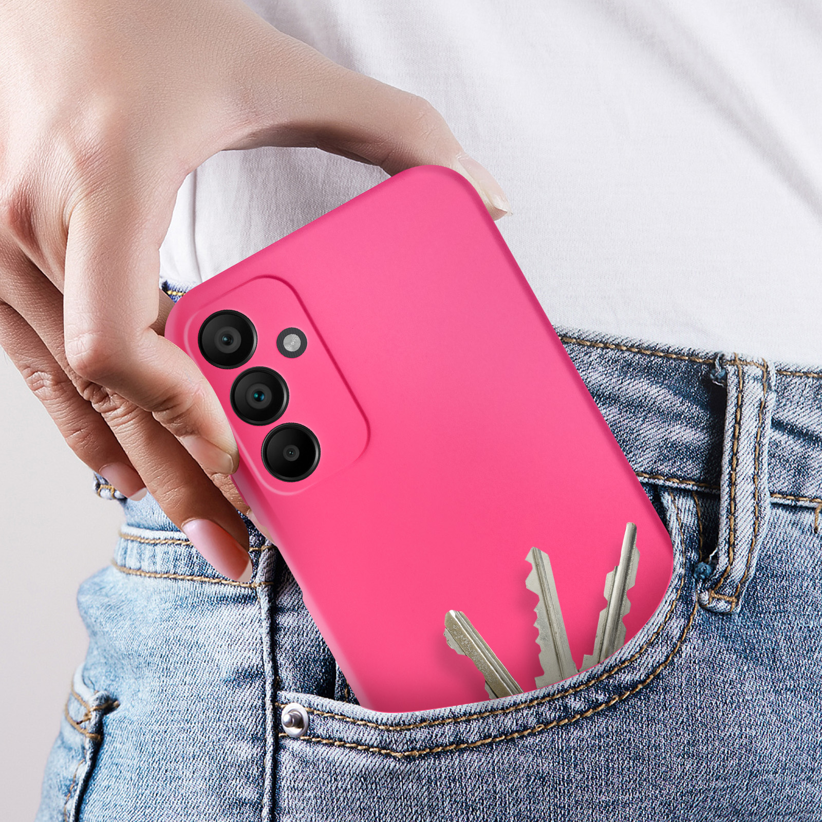 Una mano in tasca, che tiene un telefono rosa e delle chiavi. La tasca è su jeans blu.