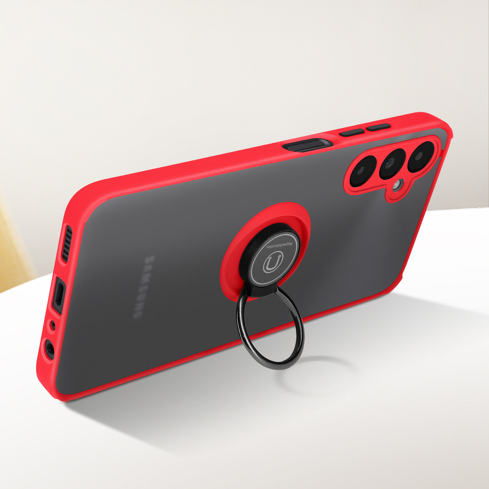 Un telefono con custodia rossa e grigia e un supporto ad anello sul retro, inclinato su superficie bianca.