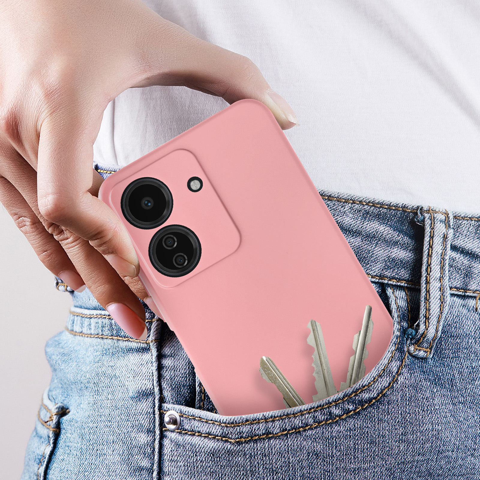 Persona che tiene un telefono rosa in tasca con chiavi visibili.