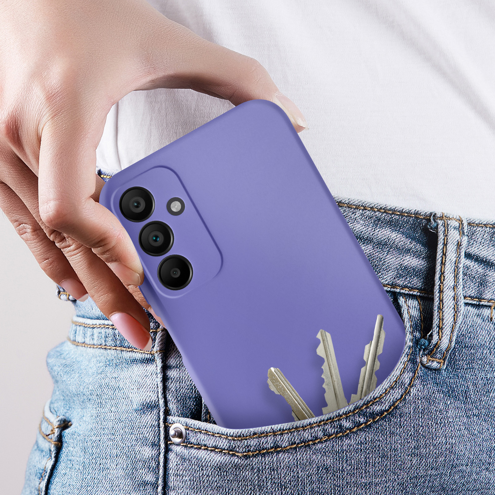 Une main tenant un téléphone violet dans une poche de jean.