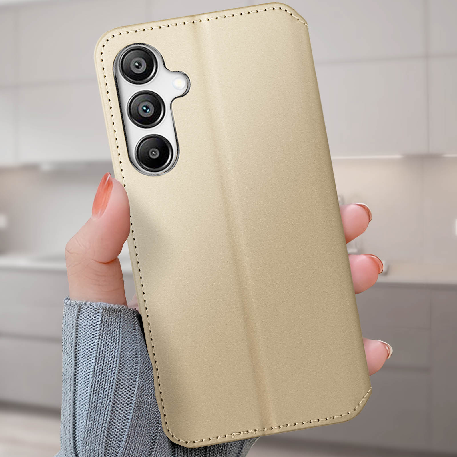 Hand hält eine goldene Handyhülle mit dreifachem Kameraausschnitt.