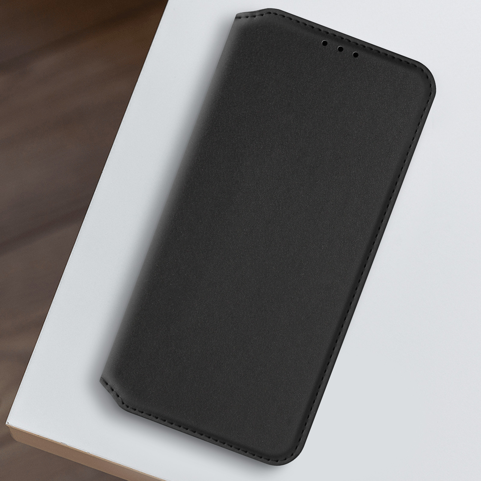 Una custodia per telefono nera con una texture simile alla pelle, aperta su una superficie bianca.