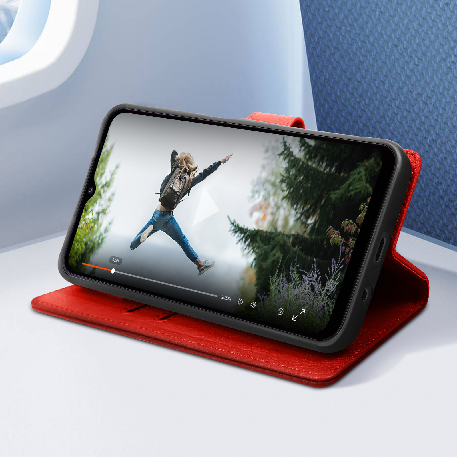 Teléfono en una funda roja mostrando una película sobre una superficie blanca, con fondo azul.