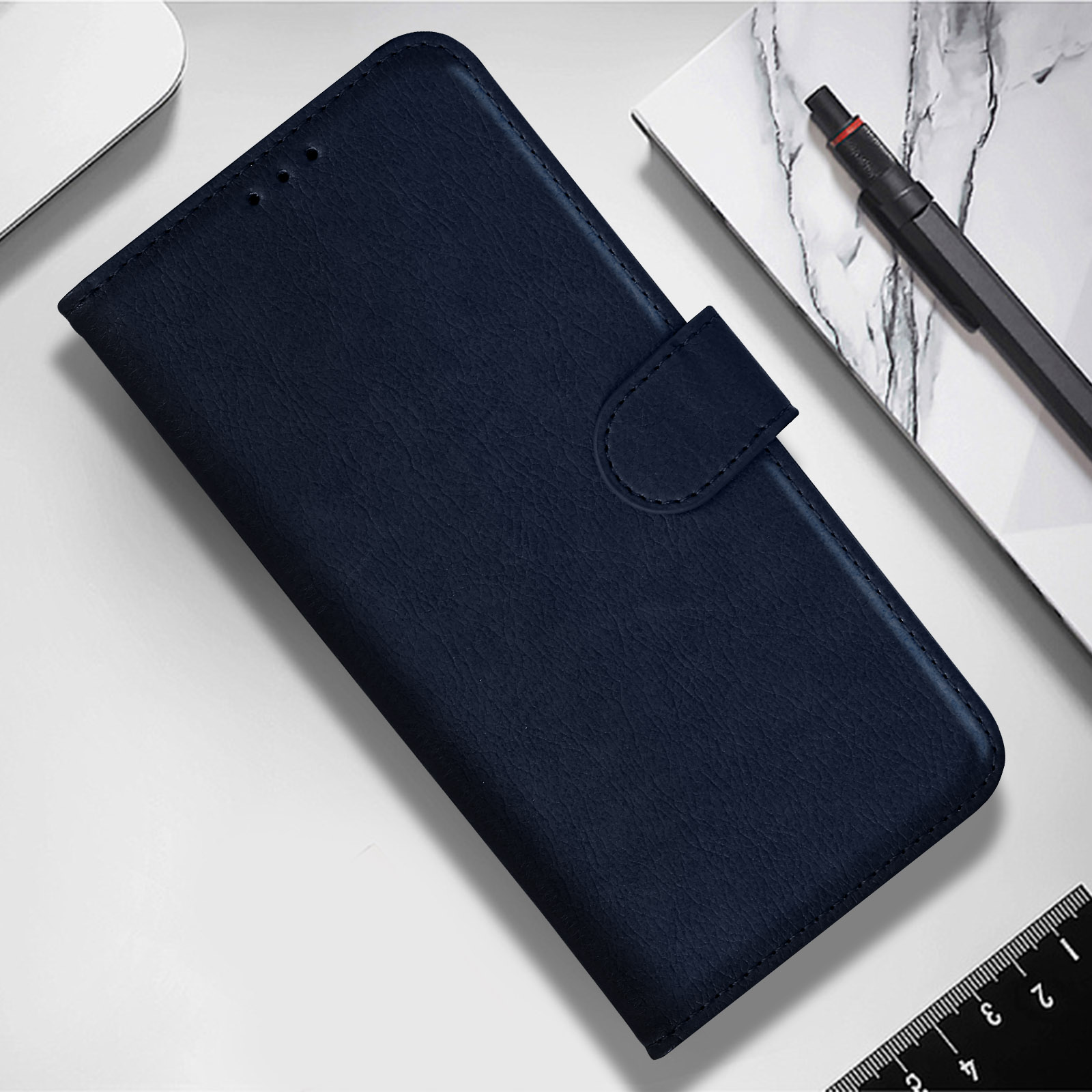 Funda azul para teléfono, cerrada, sobre superficie blanca con bolígrafo y bloc.
