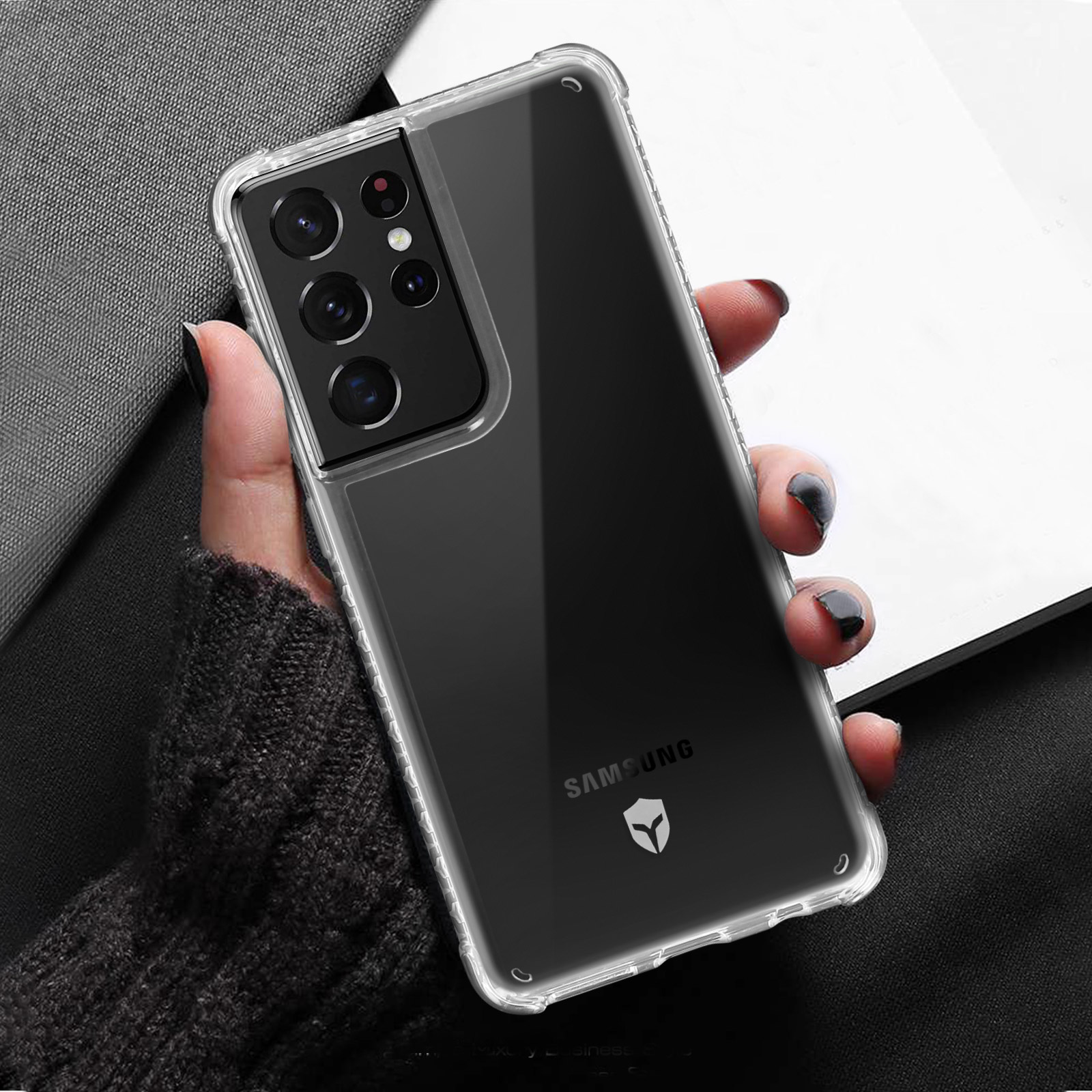 Mano che tiene una custodia trasparente, mostrando un telefono con più fotocamere posteriori.
