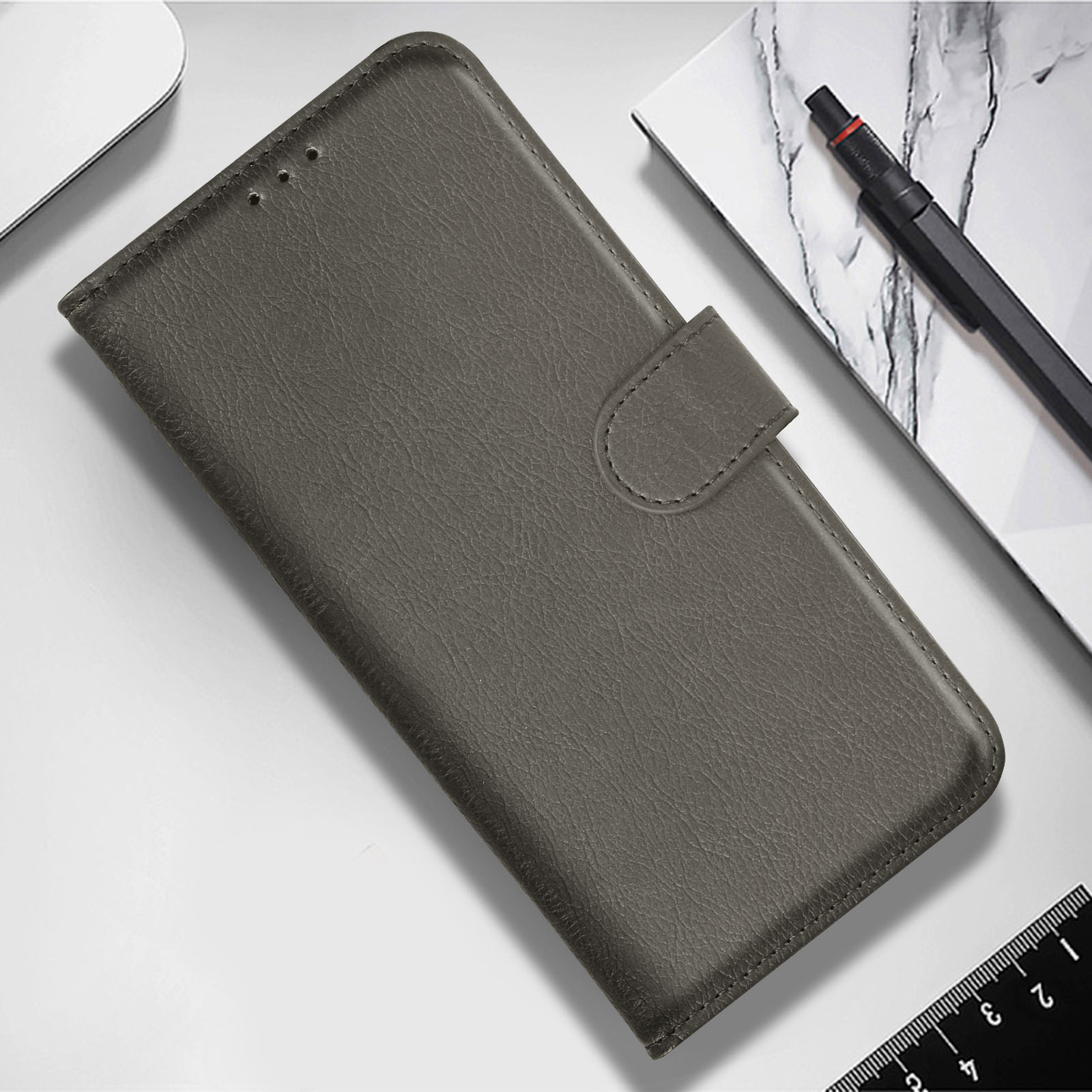 Una funda de teléfono de cuero gris, cerrada, con un cierre, sobre un escritorio.