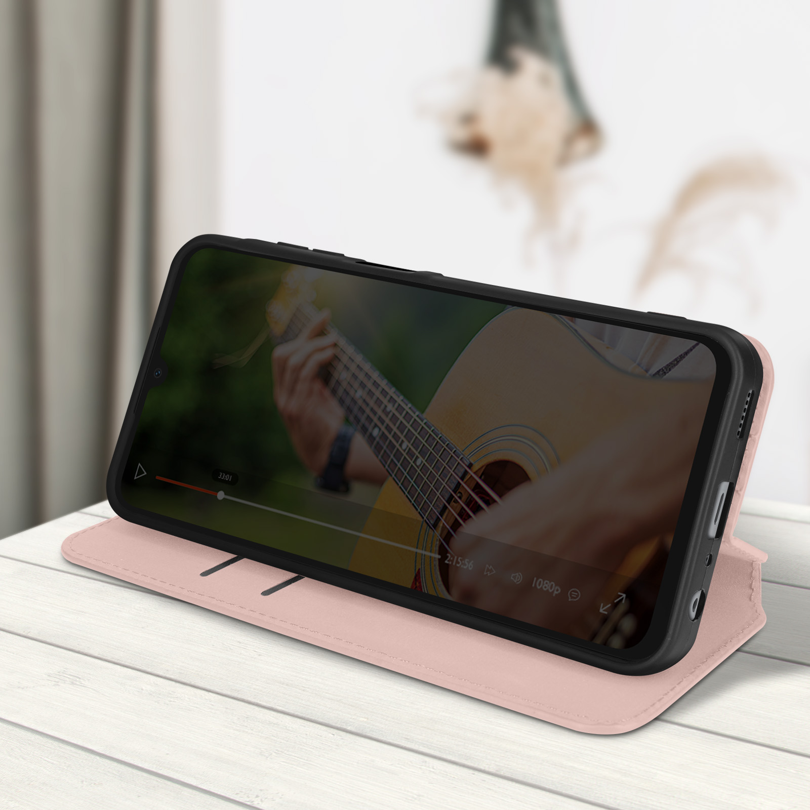 Telefono in una custodia rosa che riproduce un video. Il telefono è su una superficie di legno bianca.
