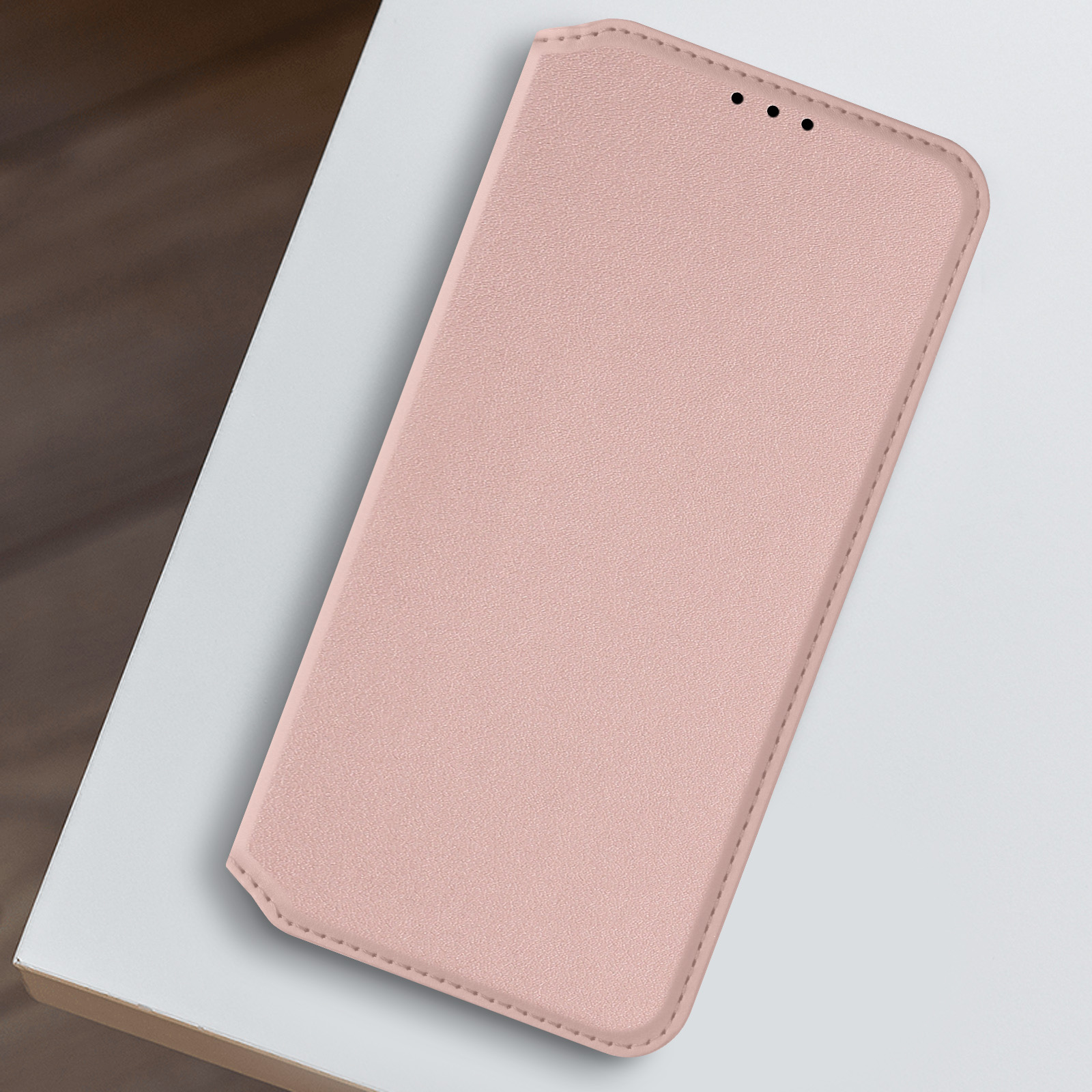 Custodia rosa per telefono su una superficie bianca. Ha una trama liscia e un design semplice.