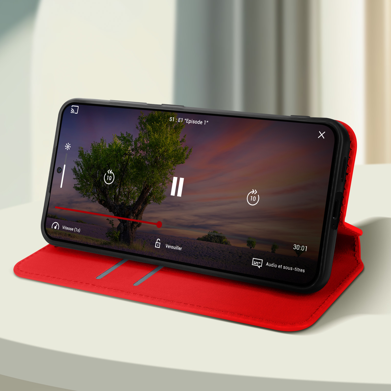 Smartphone che mostra un video con custodia rossa, su un tavolo bianco. Il video mostra un albero e controlli.