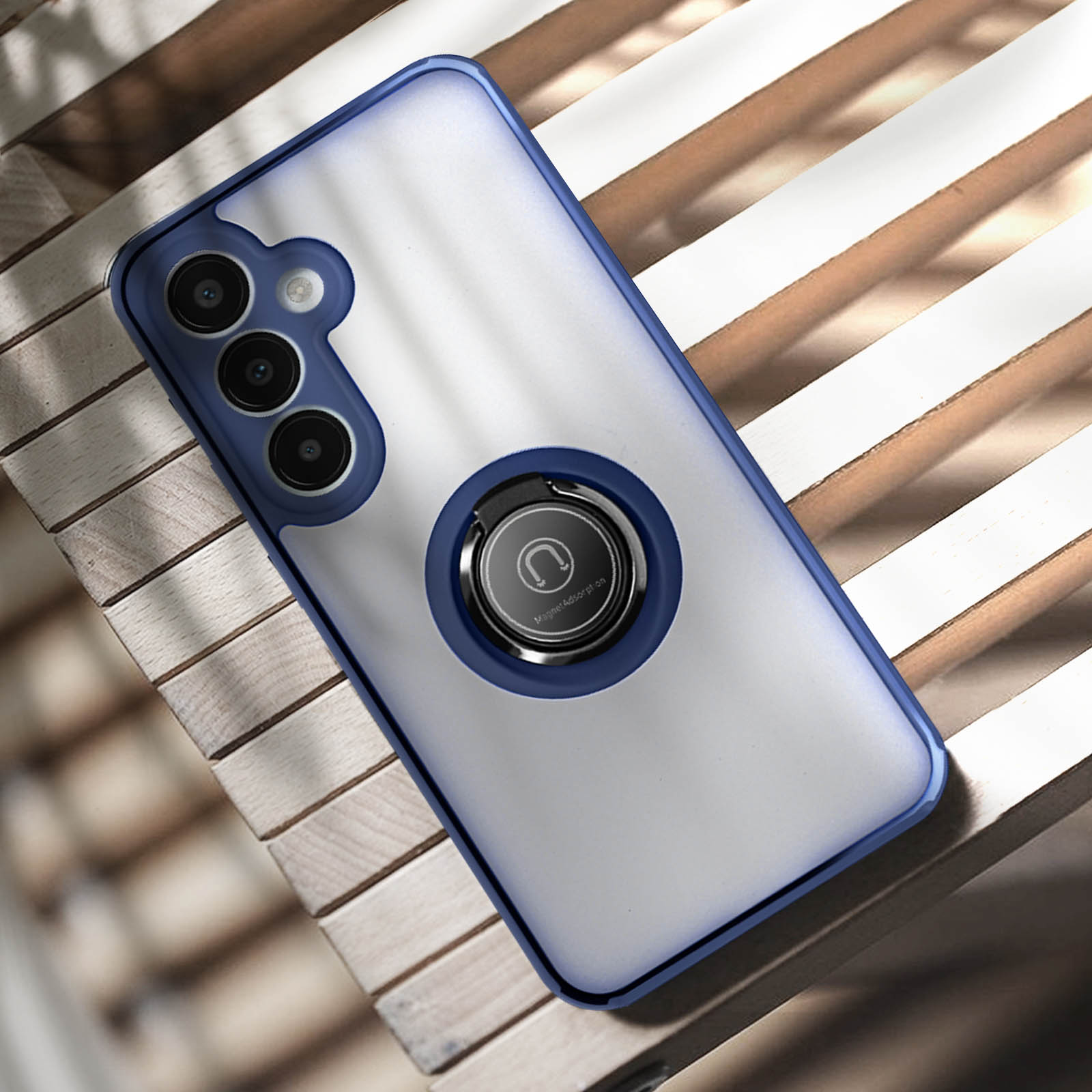 Un telefono con custodia blu con supporto ad anello, appoggiato su una superficie di legno, con una finestra sullo sfondo.