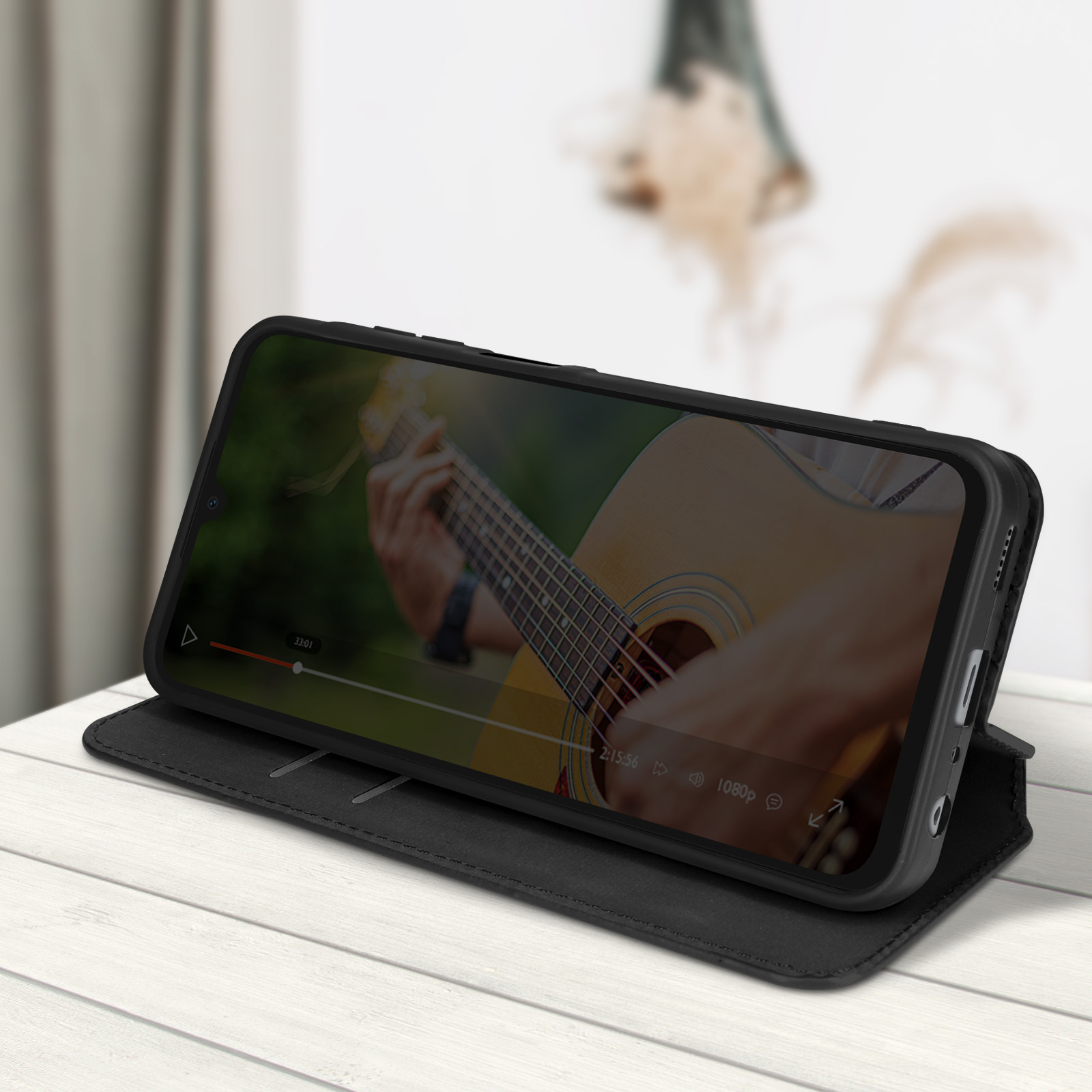 Ein schwarzes Telefon in einem Etui ist auf einem weißen Tisch geöffnet und spielt ein Gitarrenvideo ab.