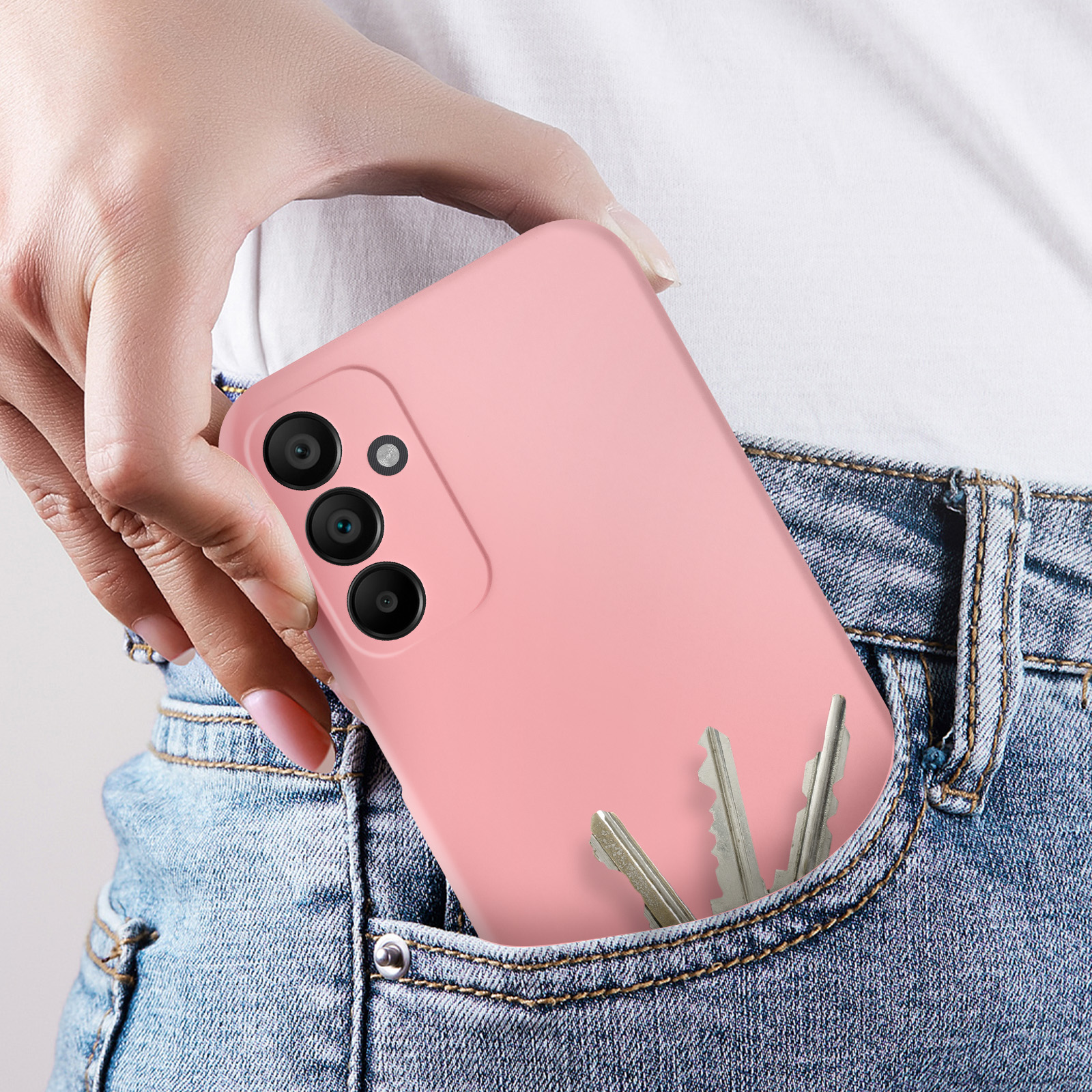 Una mano che tiene una custodia rosa con chiavi nella tasca di jeans blu.