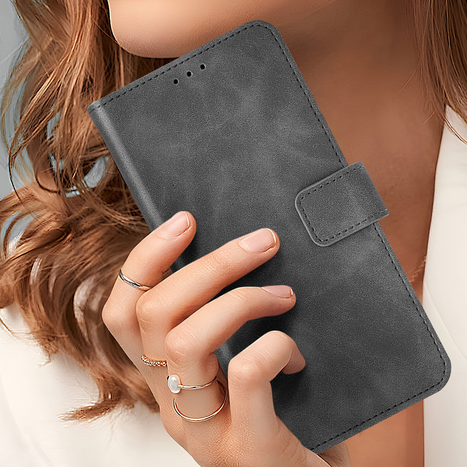 Una custodia per telefono grigia con chiusura magnetica. Una mano tiene la custodia aperta.