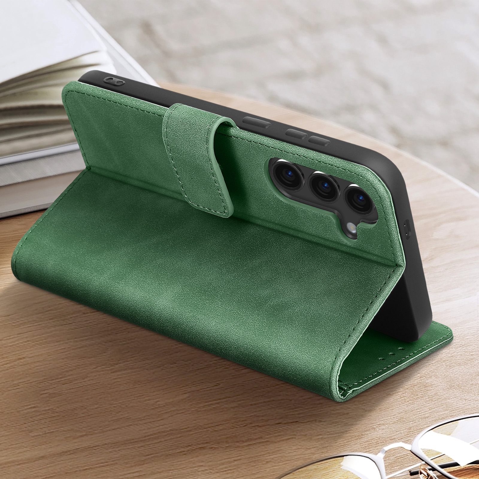 Custodia verde per telefono che supporta un telefono. È appoggiata su una superficie di legno. Lo sfondo è sfocato.