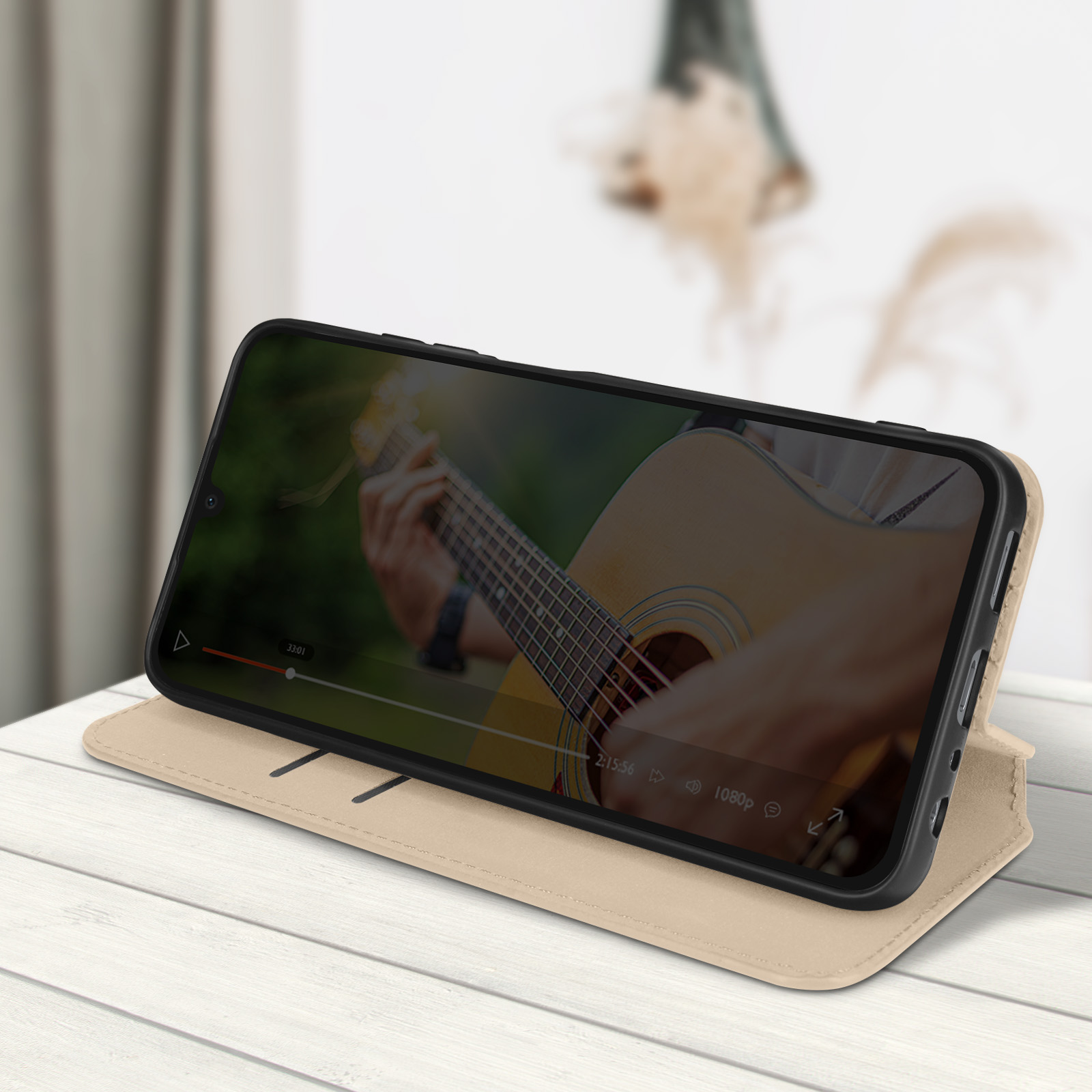Il telefono mostra un video di una chitarra. È all'interno di una custodia beige su un tavolo di legno bianco.