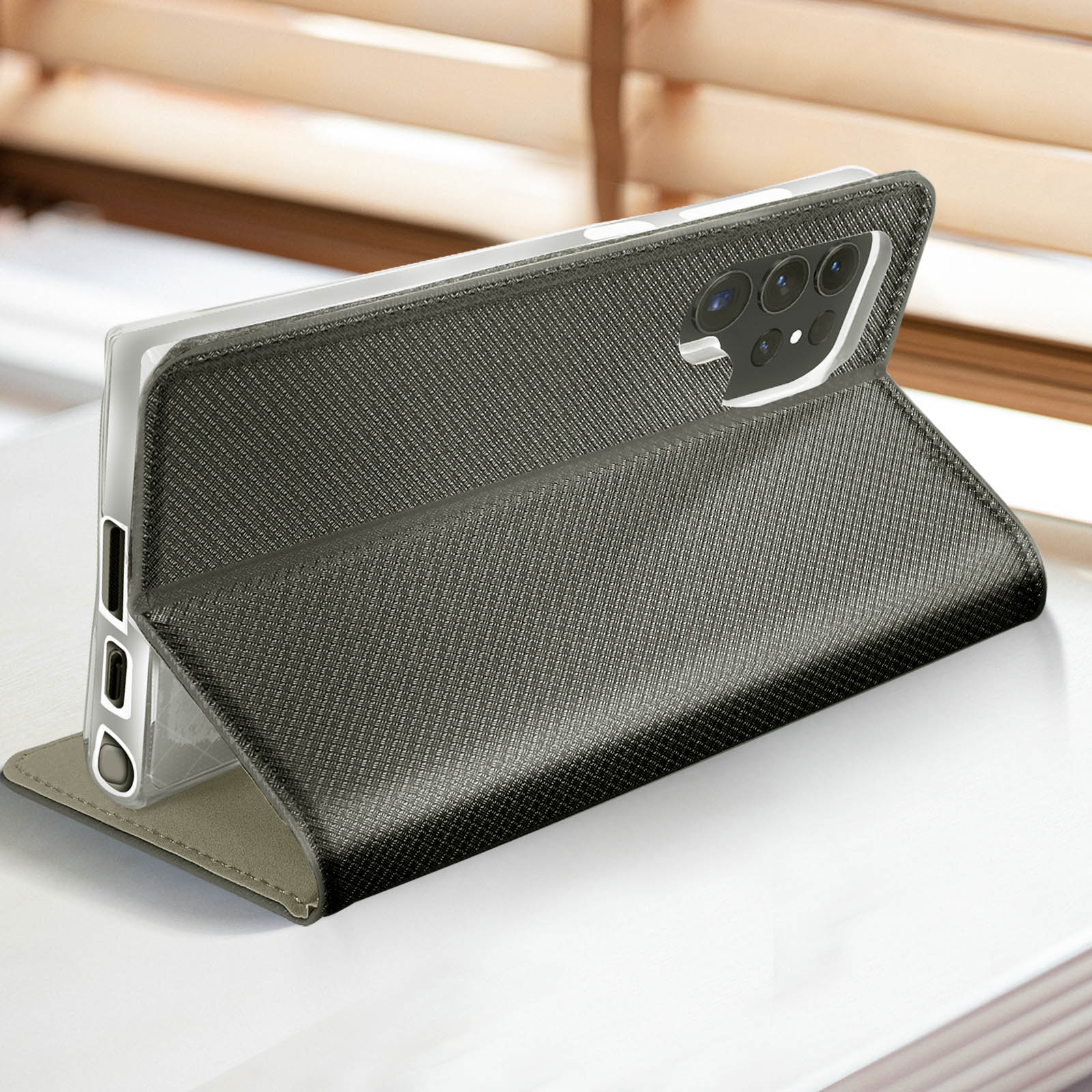 Téléphone dans un étui, en position verticale. L'étui est gris foncé, avec une texture.