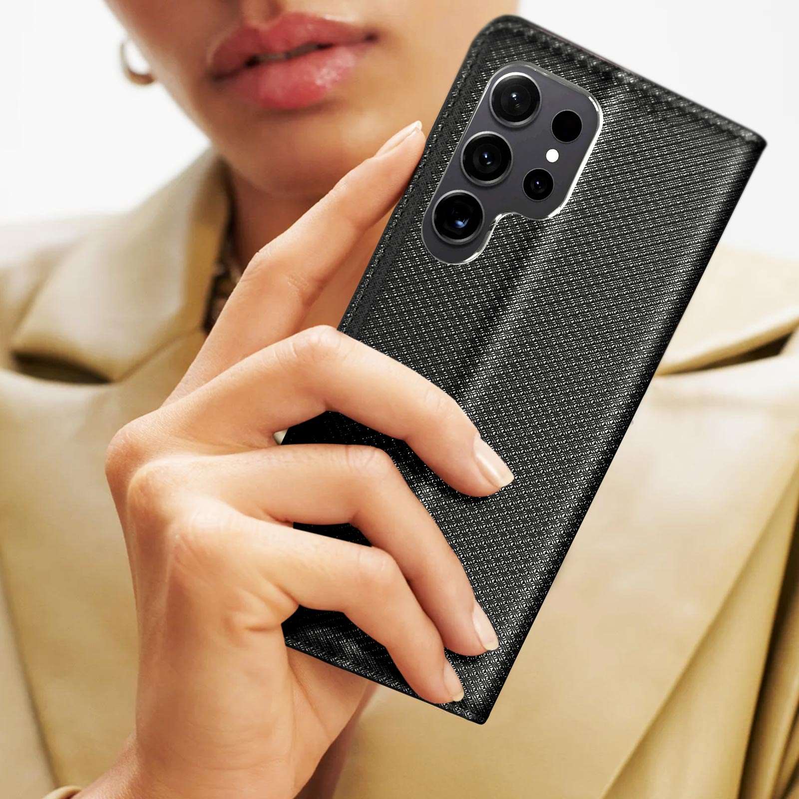 Une femme tient un téléphone noir dans un étui noir texturé. Le téléphone a plusieurs caméras.