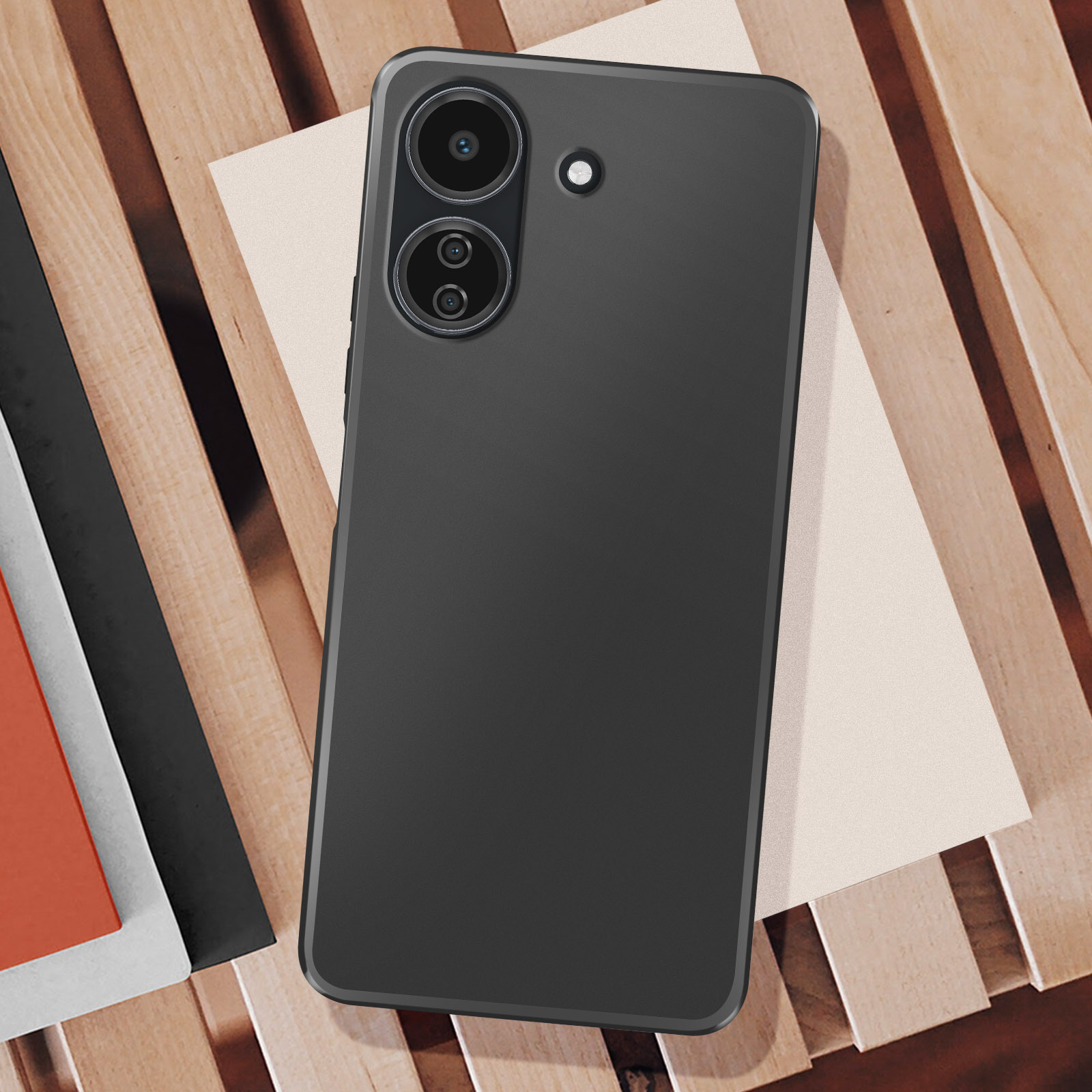 Smartphone nero su doghe di legno, con due fotocamere e un flash. Sotto c'è della carta beige.