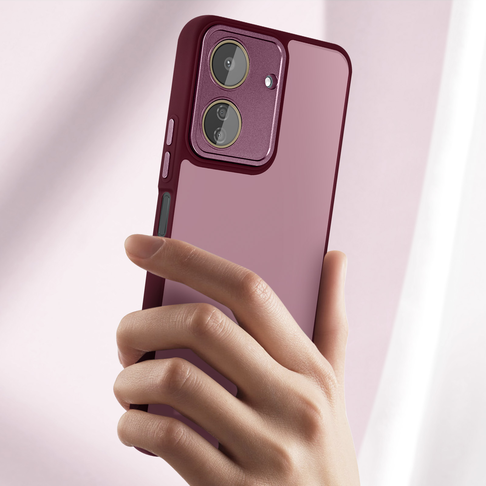 Una mano che tiene un telefono con una custodia viola. Lo sfondo è di colore rosa tenue.