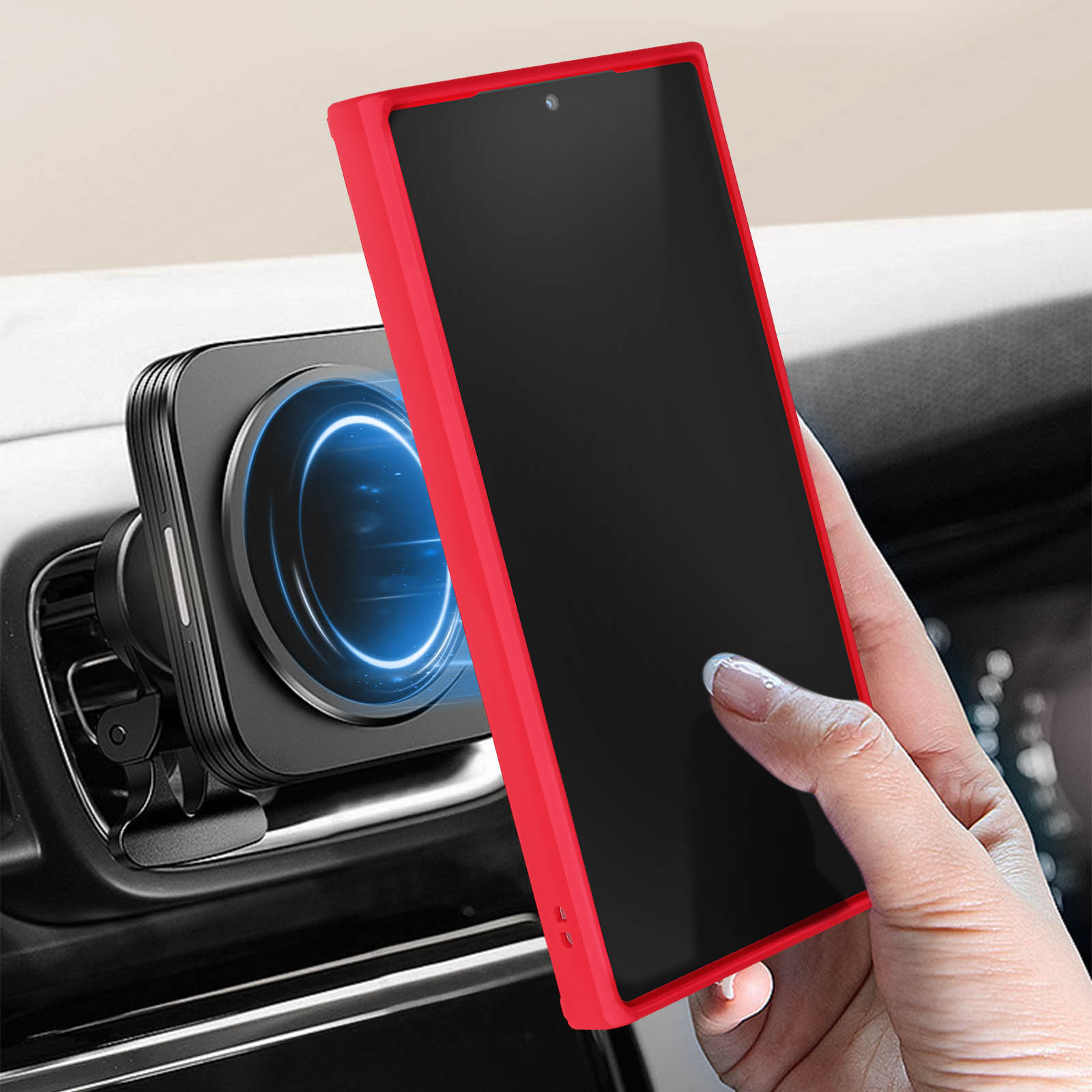 Un telefono in una custodia rossa su un supporto magnetico per auto, tenuto da una mano. Cruscotto sullo sfondo.