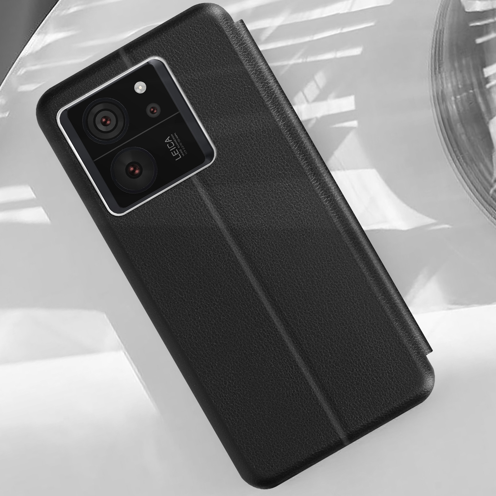 Custodia per telefono nera aperta. Ha due obiettivi della fotocamera e il logo Leica sul retro.