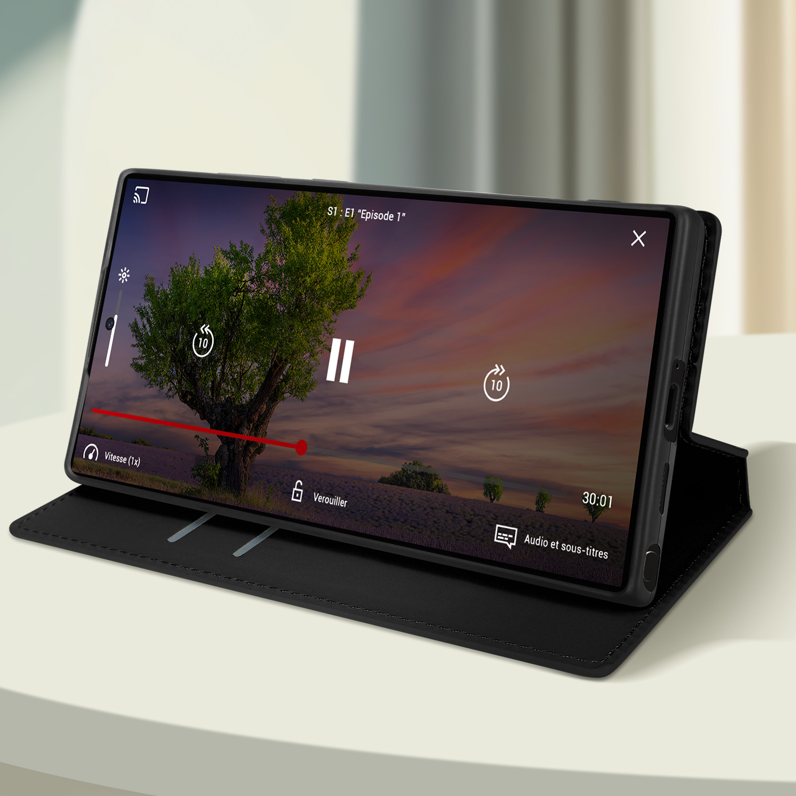 Smartphone con un video in riproduzione sullo schermo. Il telefono è in una custodia nera su un tavolo bianco.