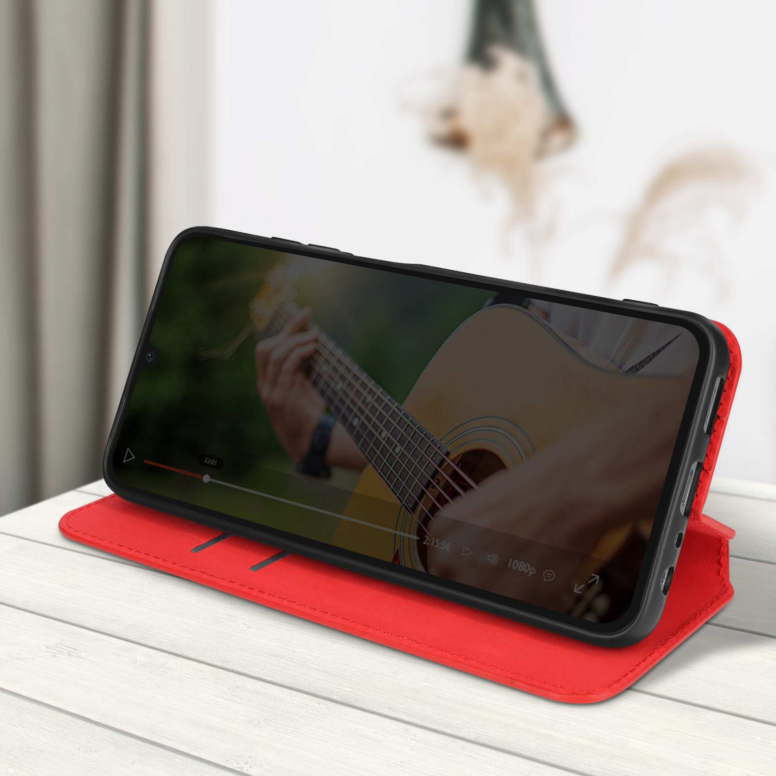 Smartphone che mostra video di un chitarrista. Il telefono è in una custodia rossa aperta. Superficie in legno.