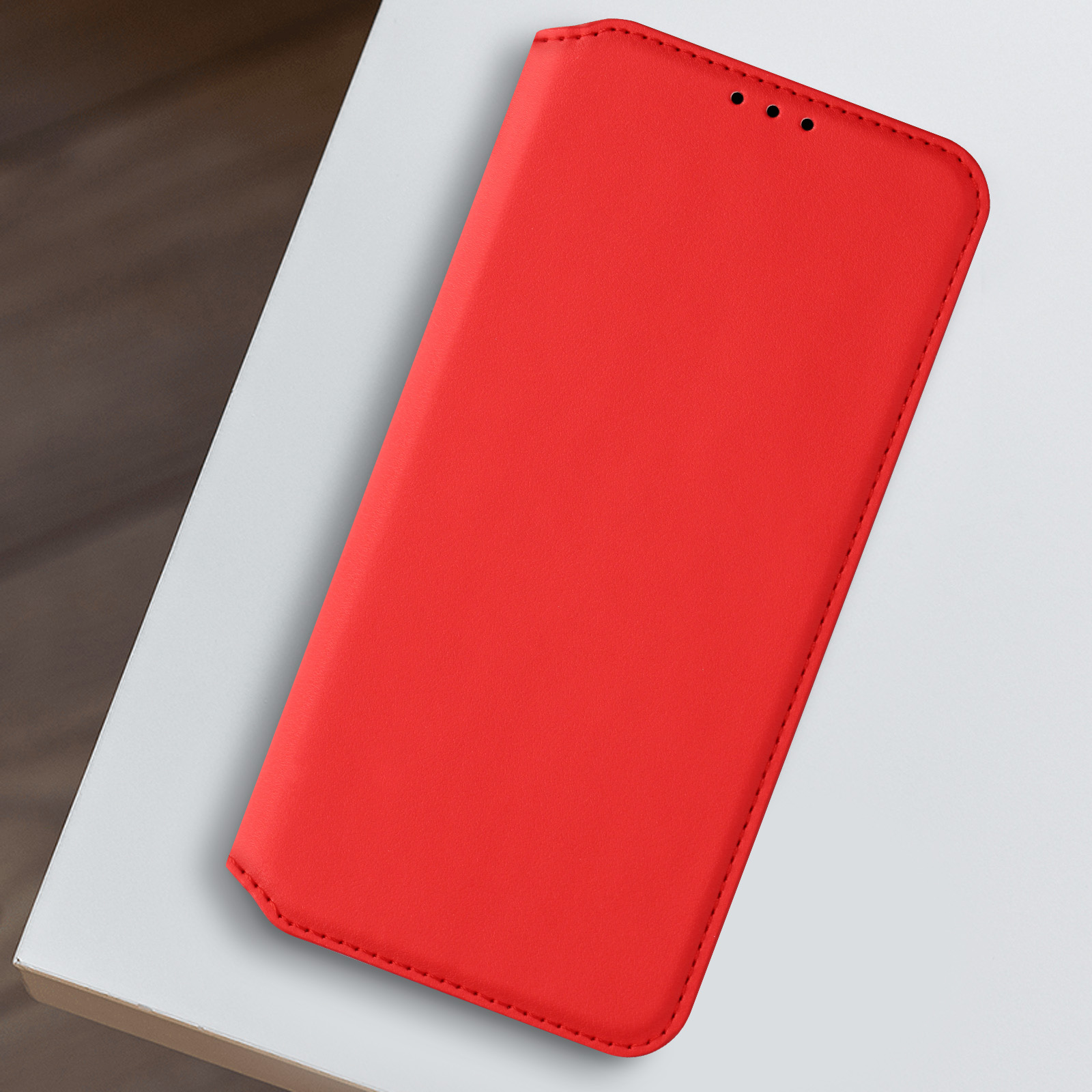 Custodia rossa per telefono su superficie bianca. Custodia chiusa.
