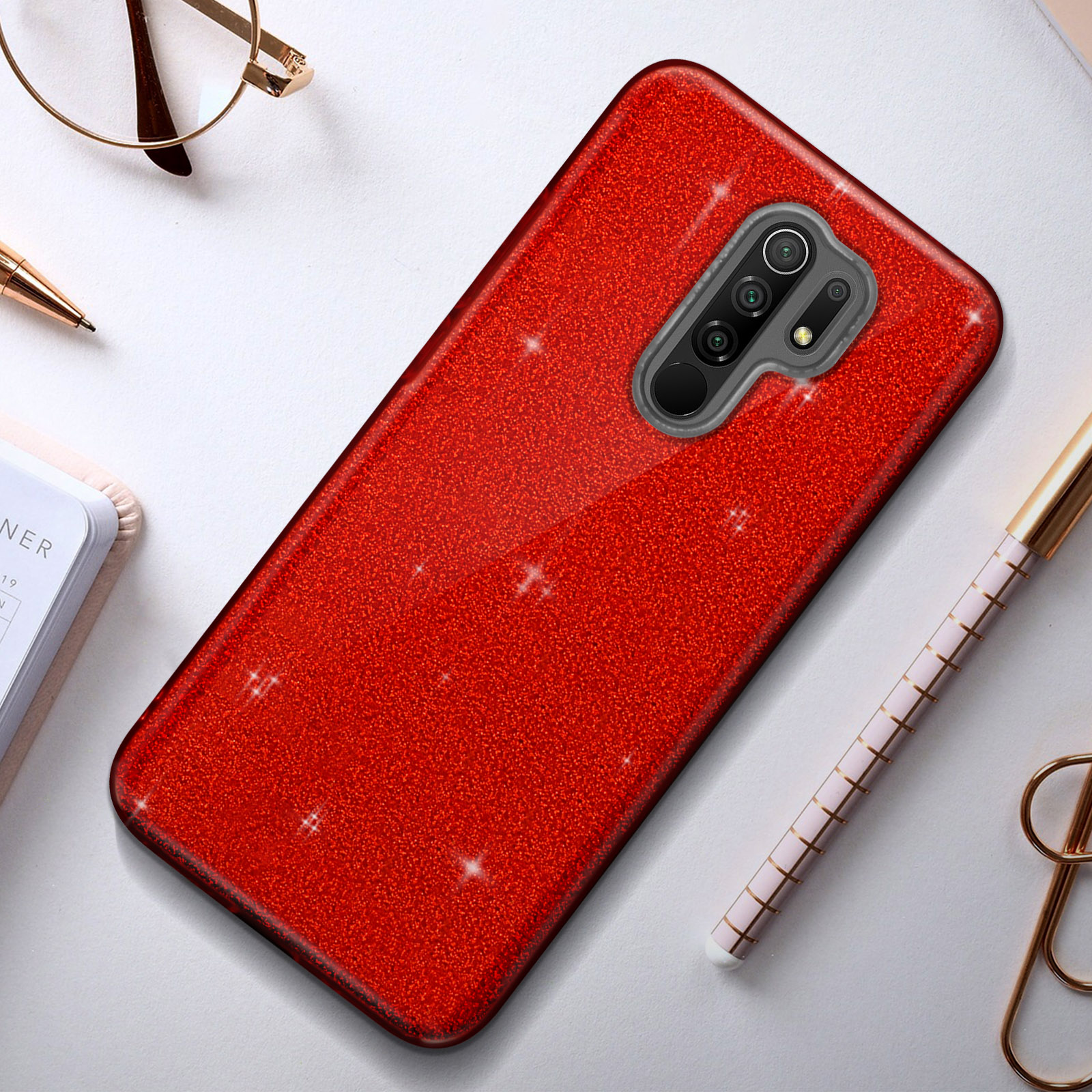 Rode glitter telefoonhoes met een rode camera-uitstulping. Andere objecten op het oppervlak.
