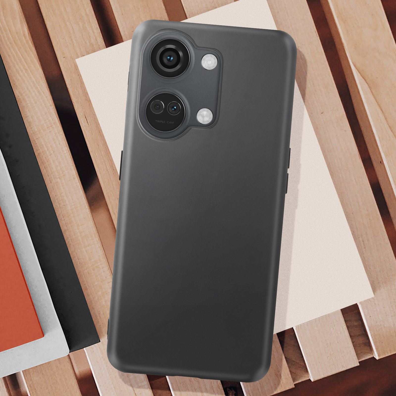 Telefono nero su superficie in legno con carta chiara. Il telefono ha un rilievo della fotocamera.