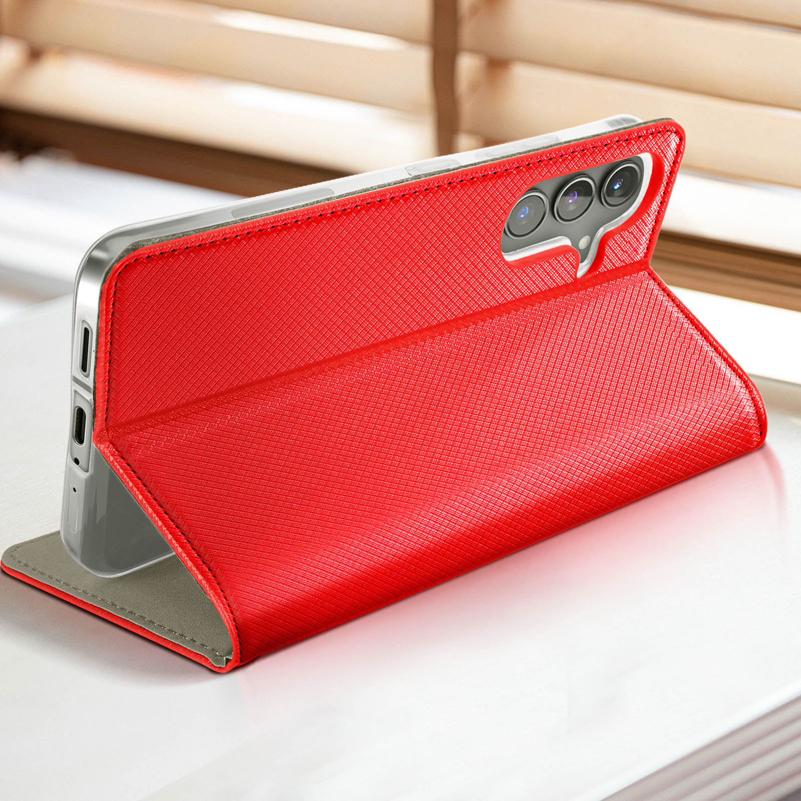 Étui de téléphone rouge, ouvert. Un téléphone est maintenu à l'intérieur. Il est sur une surface blanche.