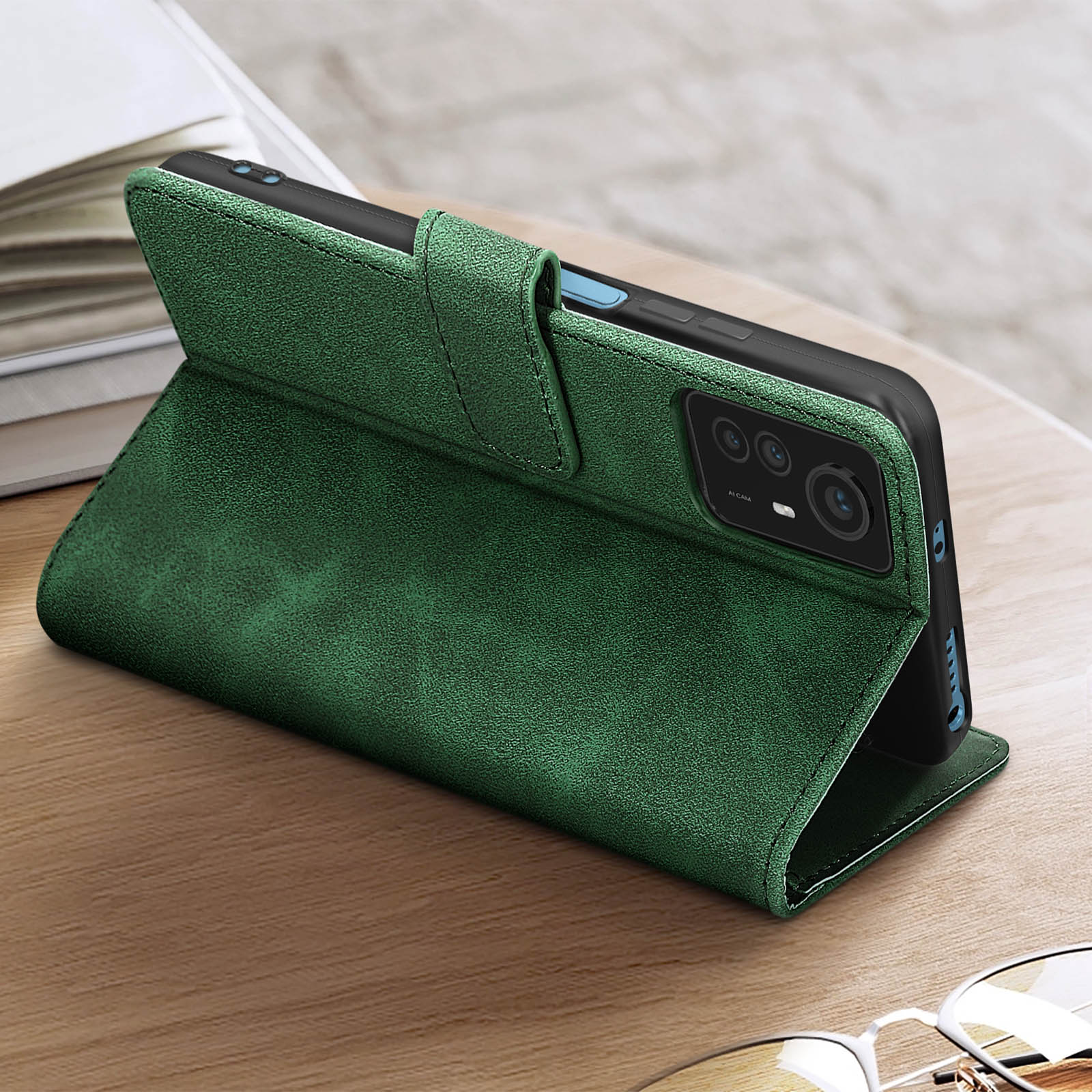 Una custodia verde aperta su un tavolo di legno. Un telefono nero all'interno.