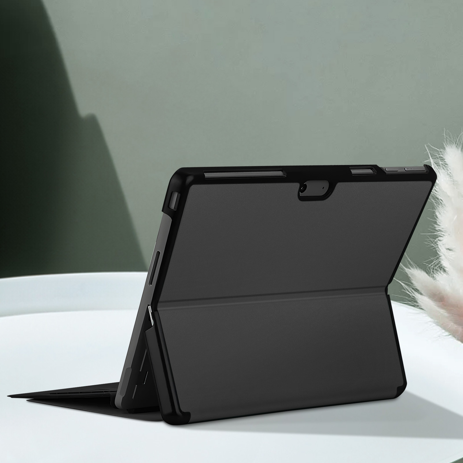 Tablette dans un étui noir sur une surface blanche. L'étui est ouvert.