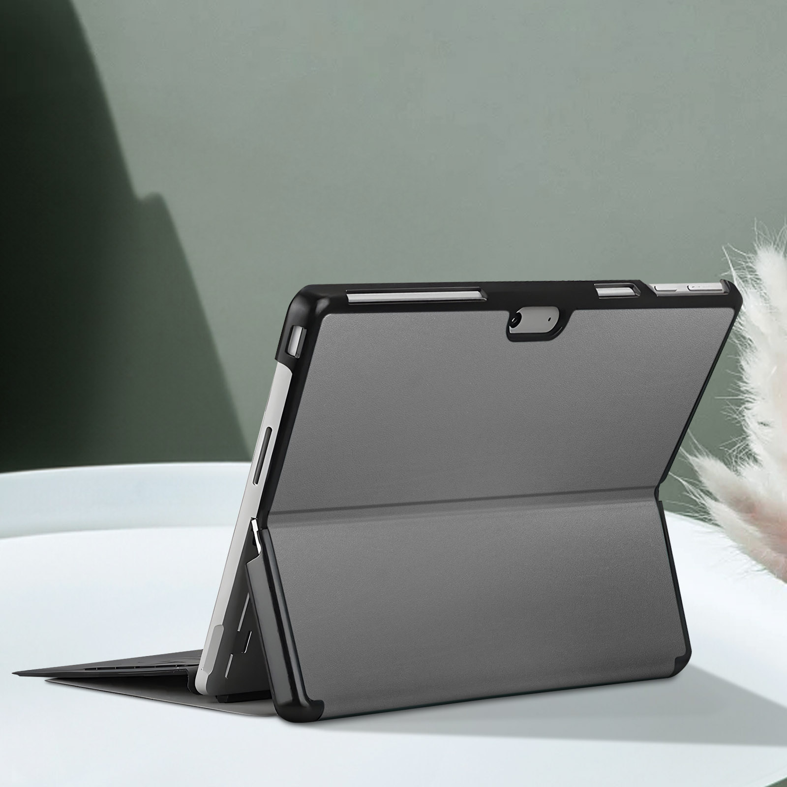 Tablet in custodia nera, aperto. Tavolo bianco, parete verde.