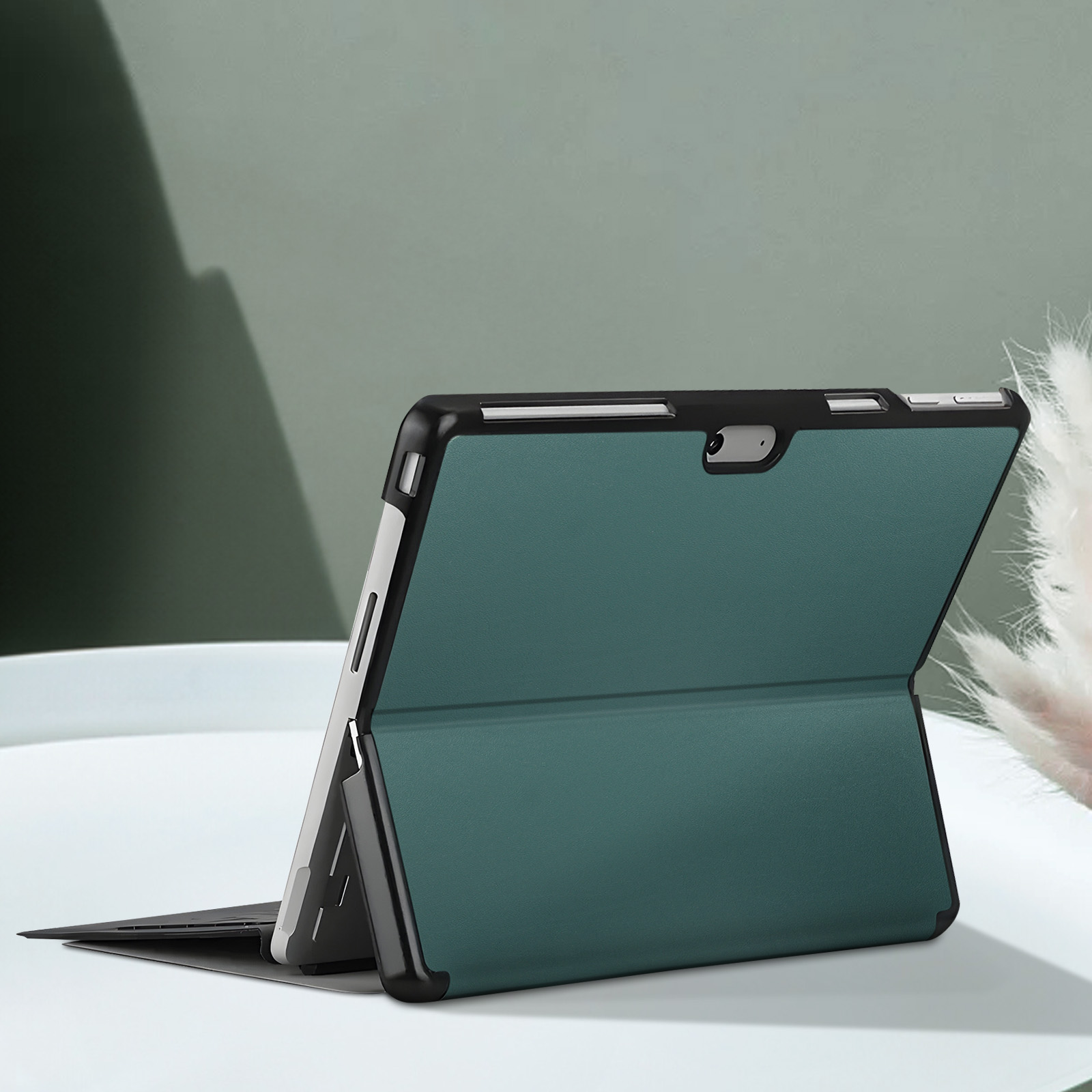 Tablet in custodia verde, aperto, su superficie bianca, sfondo sfocato.