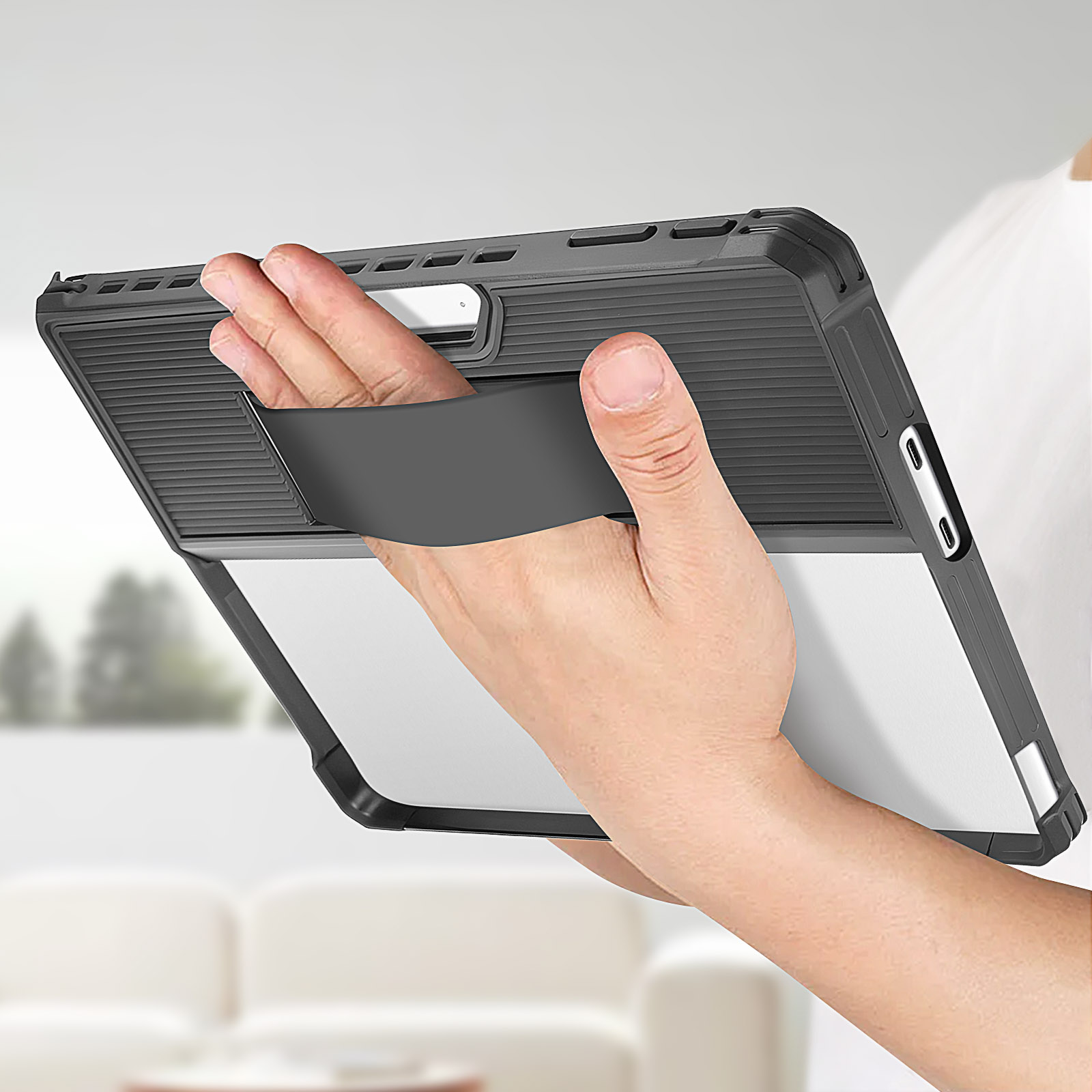 Una mano che tiene una custodia nera per tablet. La custodia ha un supporto integrato e un retro trasparente. Sfondo sfocato.