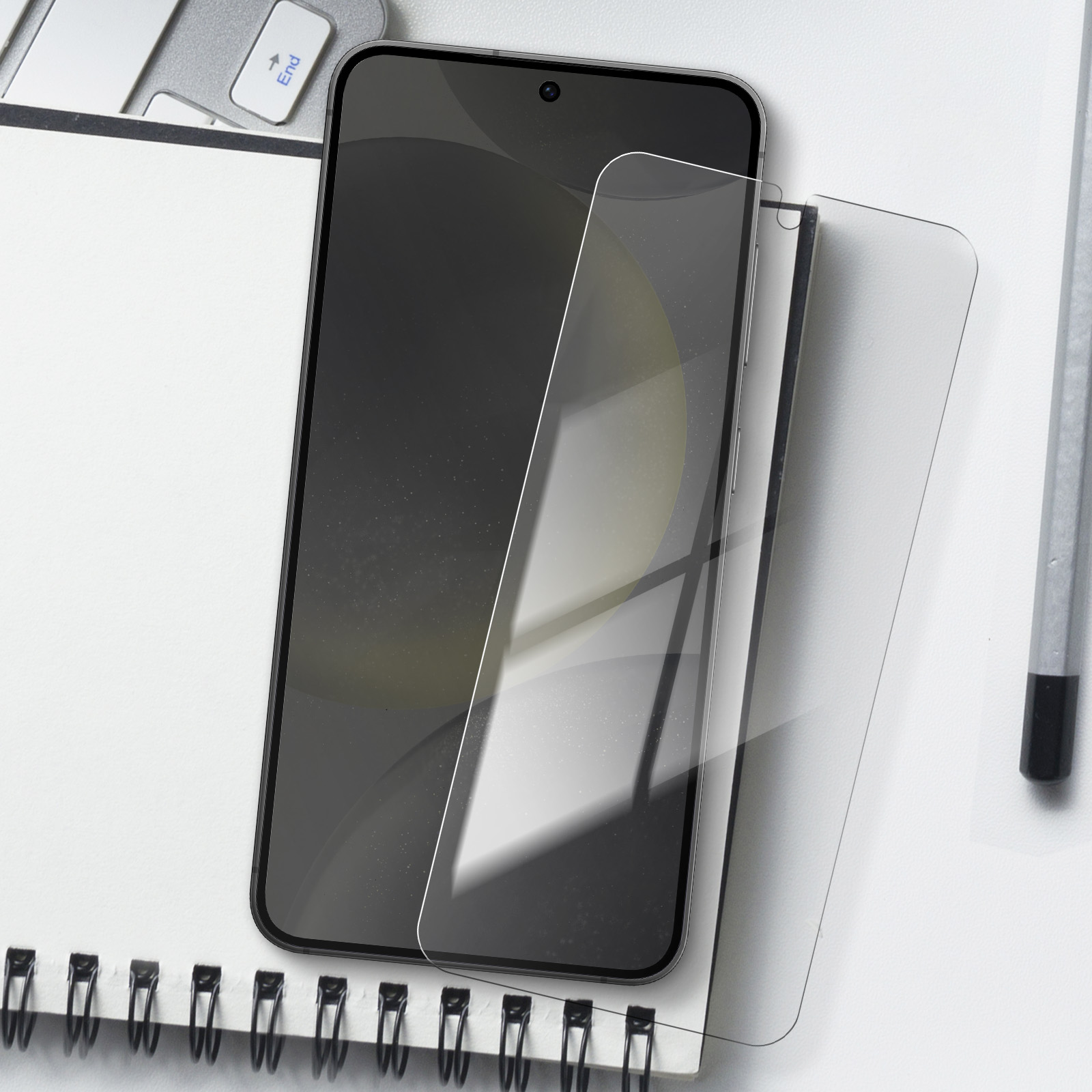Telefono con protezione schermo. Telefono su un blocco note bianco. Matita e tasto Fine sono visibili. Sfondo bianco.
