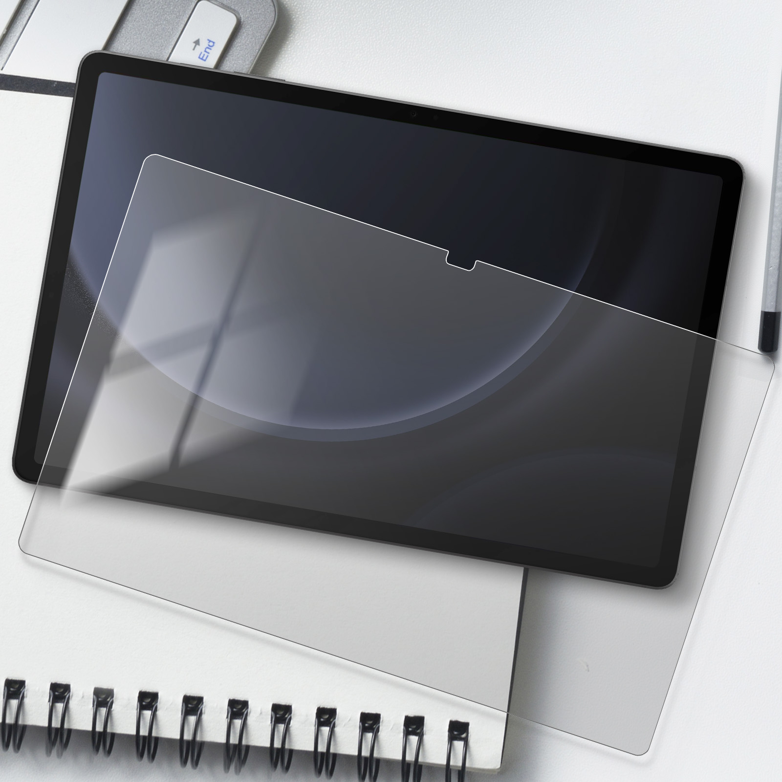 Un tablet con una protezione per lo schermo sopra, su un quaderno bianco.