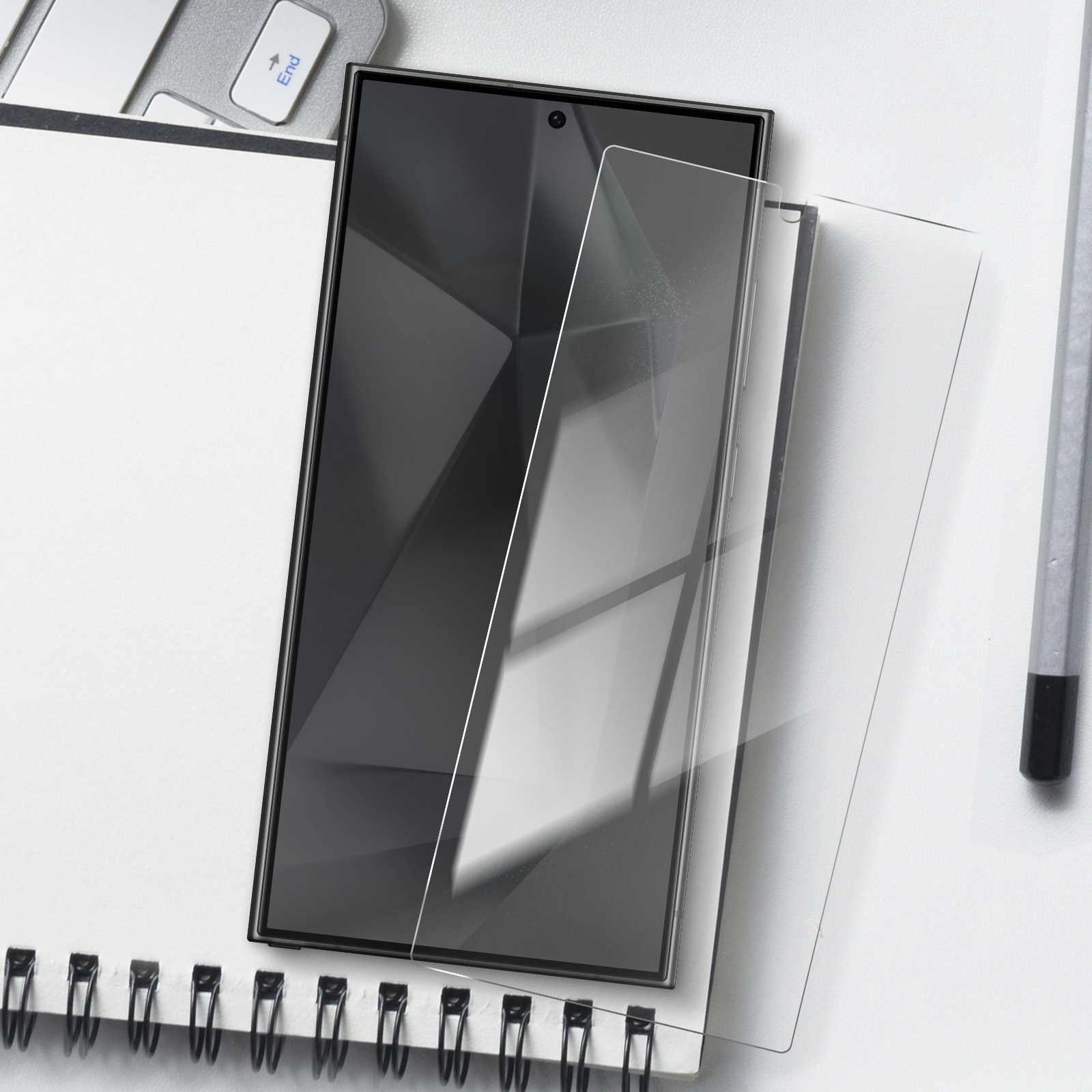 Un telefono con una protezione per lo schermo è posizionato su un quaderno, con una penna.