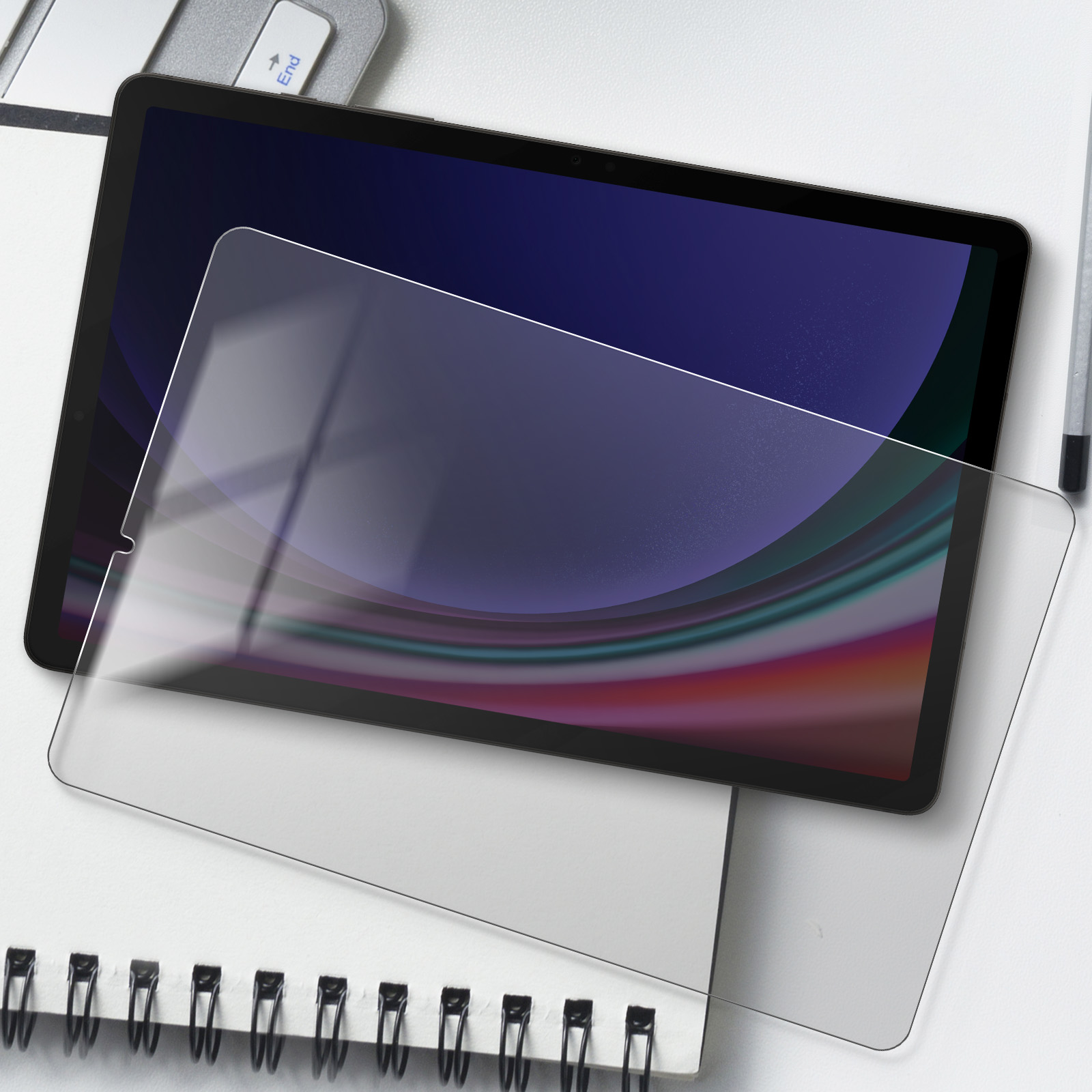 Tablet con protezione schermo. Il tablet è su una superficie bianca e un taccuino sotto.