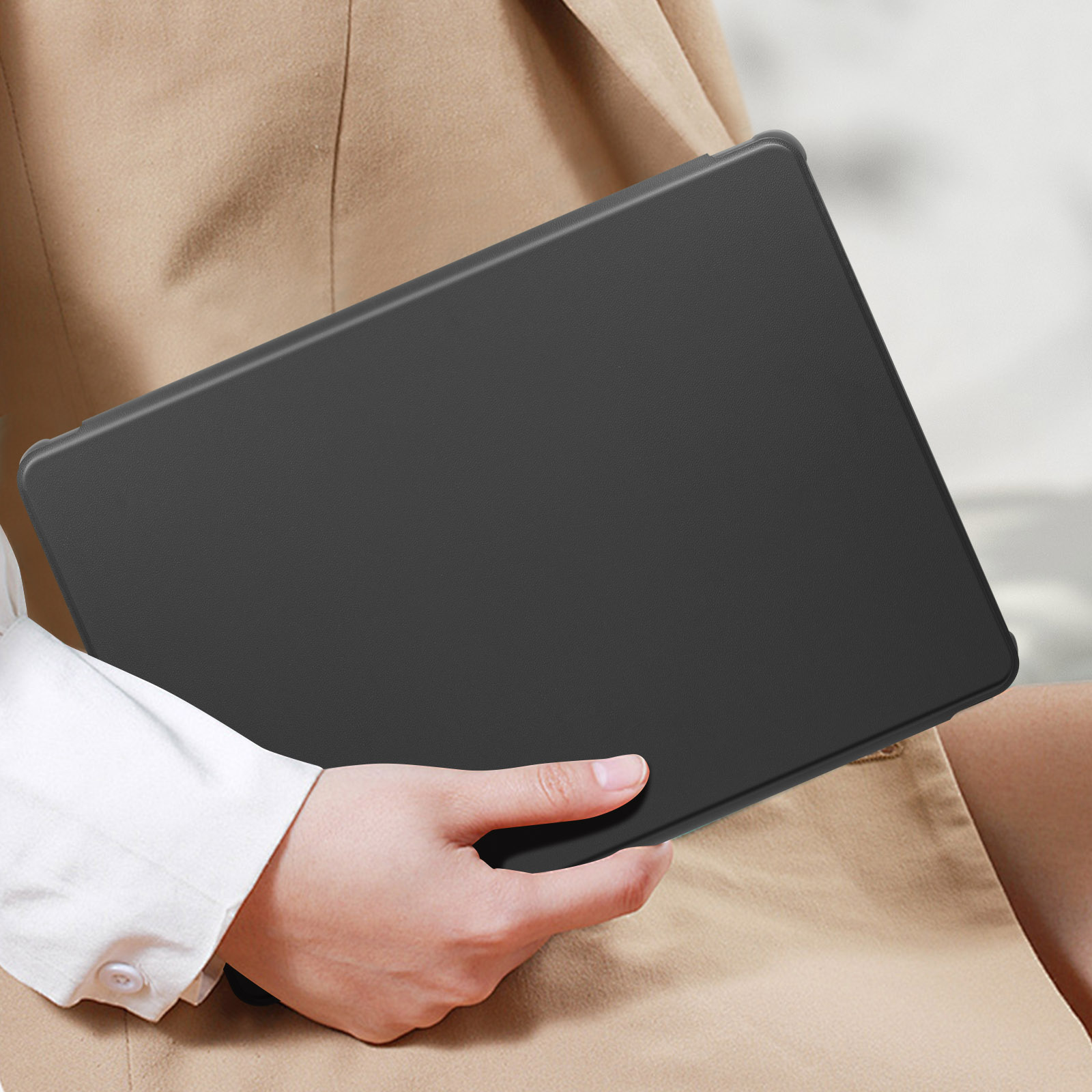 Una persona tiene in mano un tablet nero. Indossa un blazer beige e una camicia bianca.