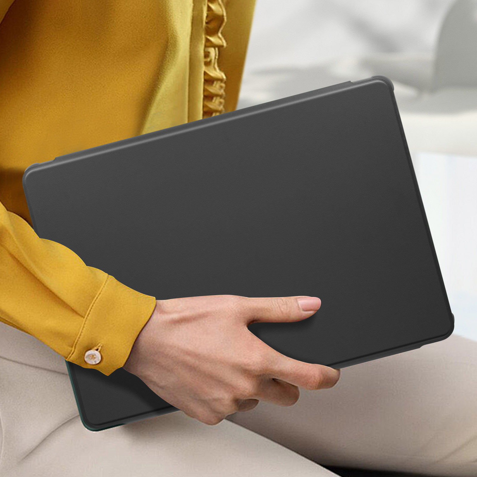 Una persona che tiene una custodia per tablet nera. La persona indossa una camicia gialla.