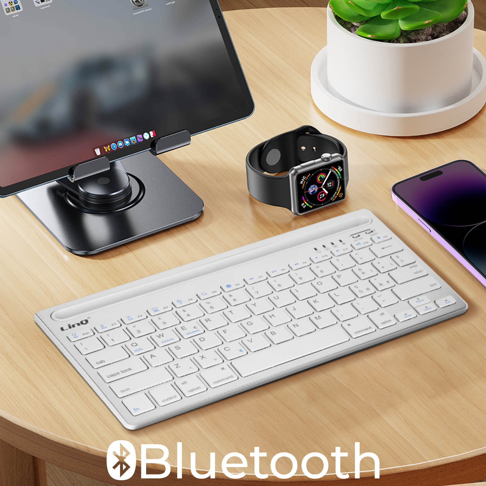 Weiße Tastatur und Uhr auf einem Holztisch. Ein Tablet auf einem Ständer und ein Telefon sind ebenfalls vorhanden.
