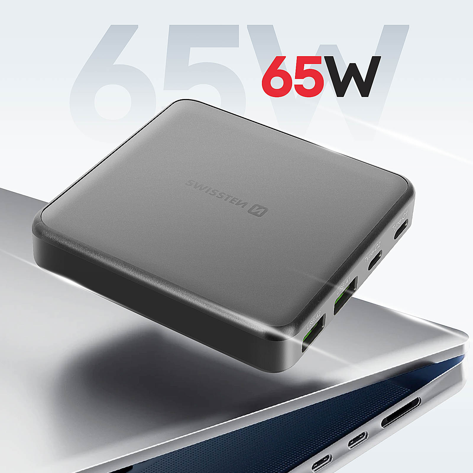Eine graue Powerbank mit 65W-Etikett. Es liegt auf einer Laptop-Oberfläche mit sichtbaren Anschlüssen.