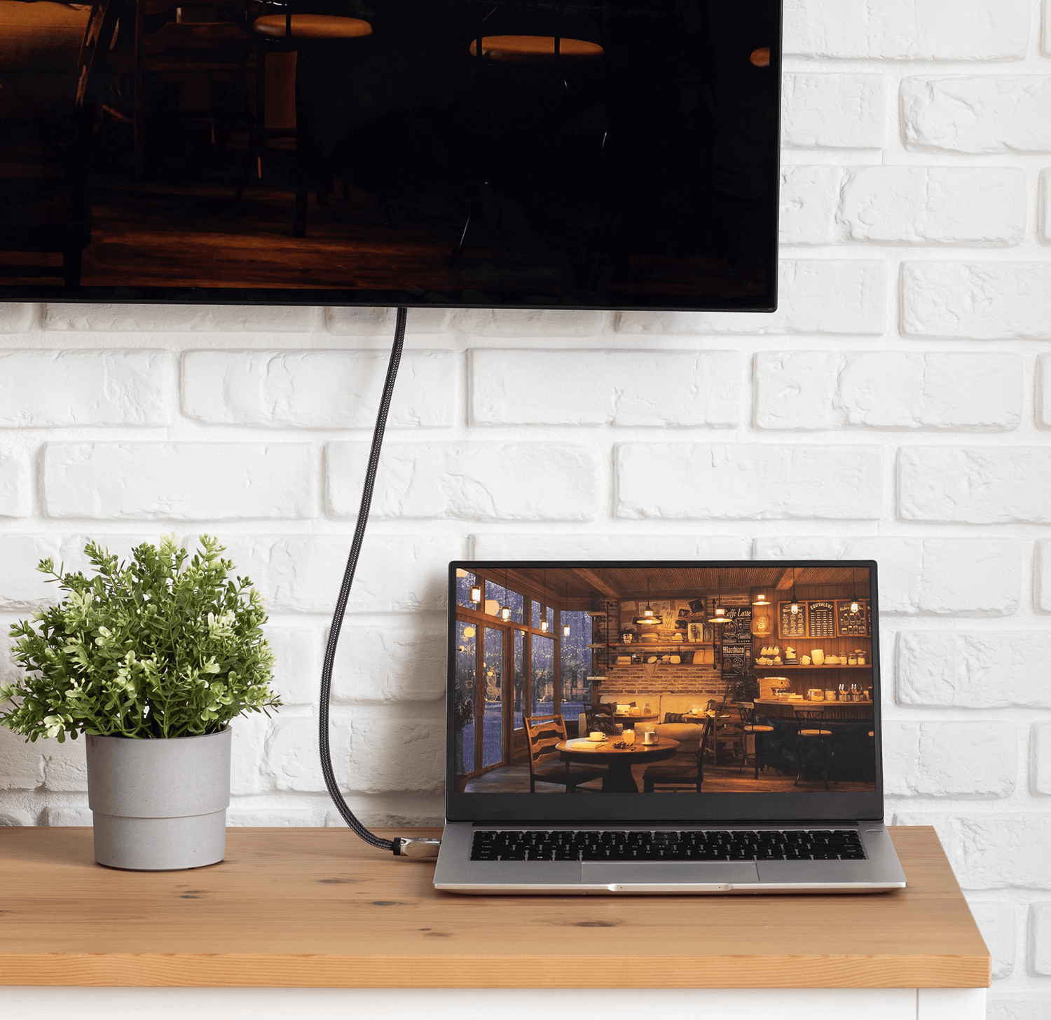 Laptop wyświetlający wnętrze restauracji podłączony do telewizora na stole.