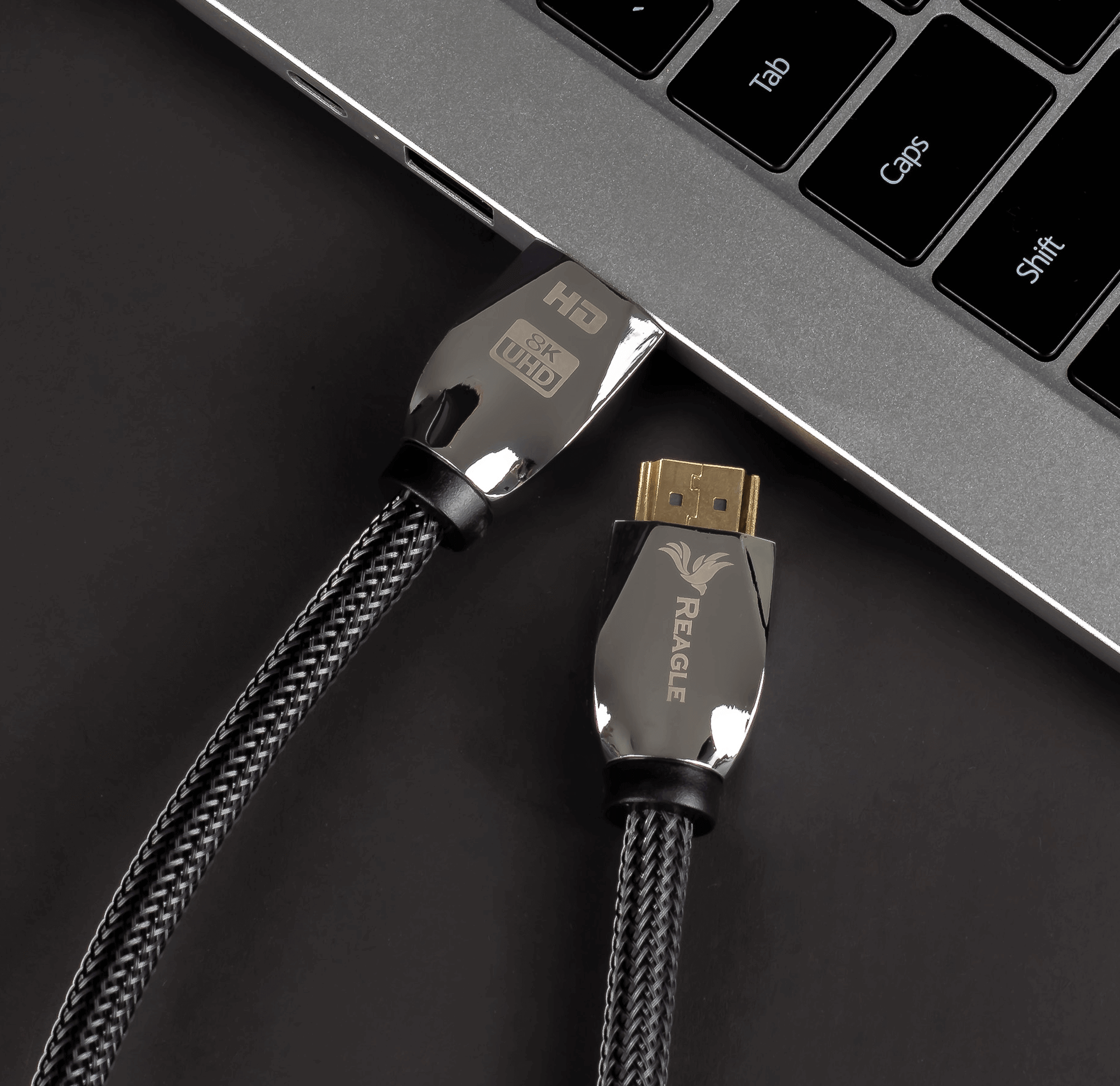 Kabel HDMI podłączony do laptopa. Kabel jest czarny i ma logo Reagle.